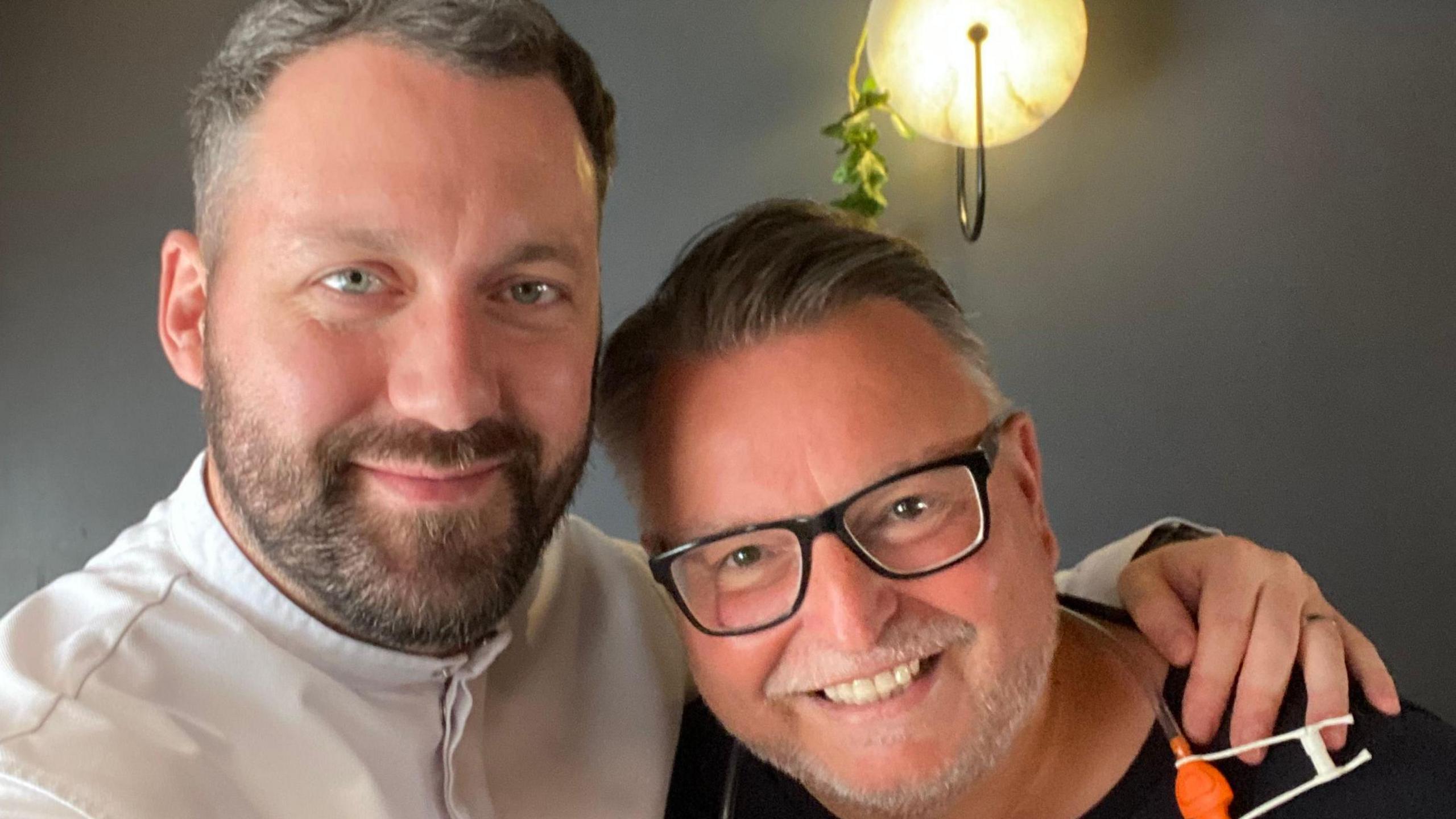 A selfie of Michelin-starred chef Tom Shepherd with his arm around Matt Davies - both men have beards, with Tom wearing chef's whites and Matt has glasses on