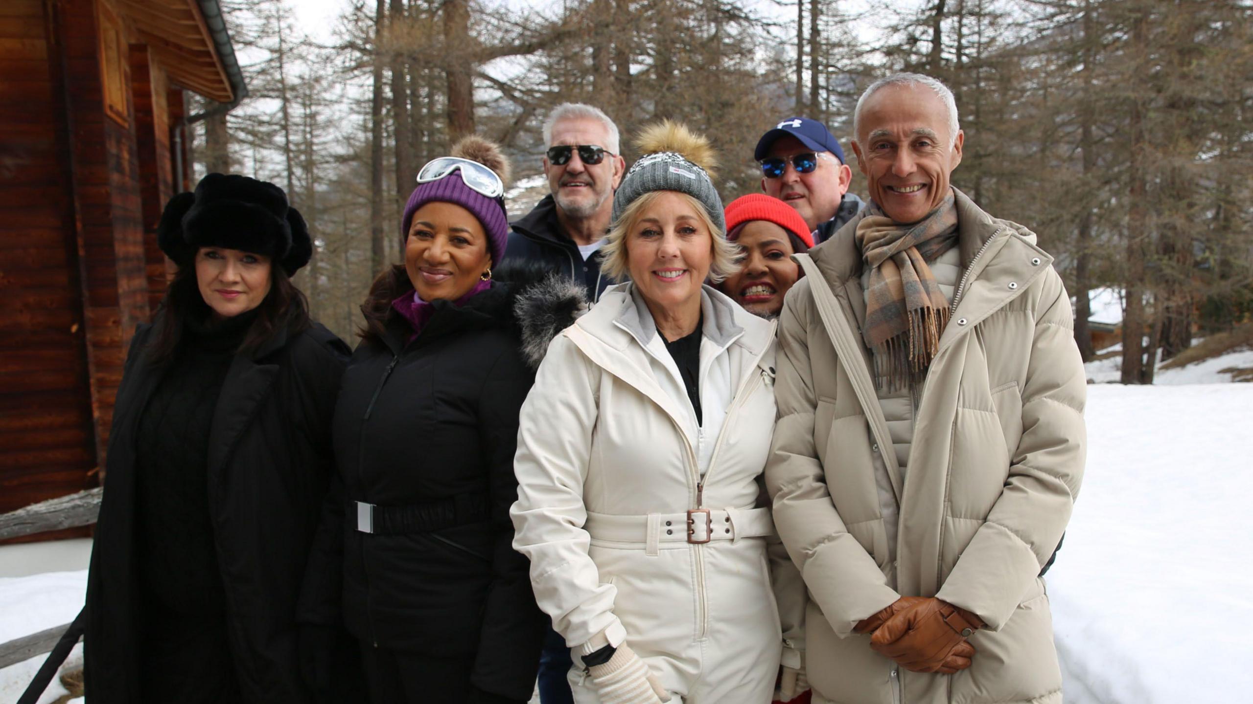 Group picture of Last Christmas music video stars Cheryl Harrison, Pepsi Demacque Crockett, David Ridler, Shirlie Kemp, Pat Fernandes, Jonny Fowler, Andrew Ridgeley outside the wooden chalet amid the snowy woods