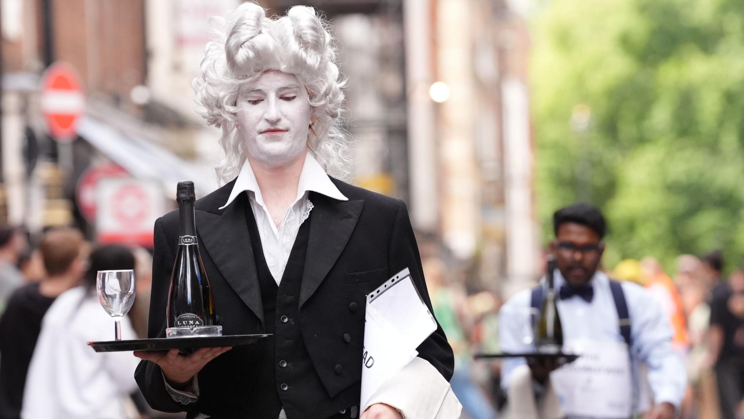 A man in white face make takes part in a waiters race in Soho