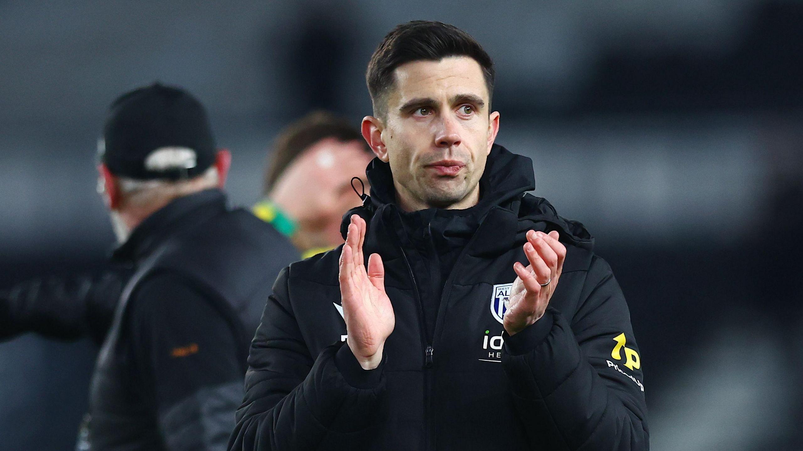 Eric Ramsay applauding the fans while wearing a black West Bromwich Albion jacket following the side's draw with Derby County