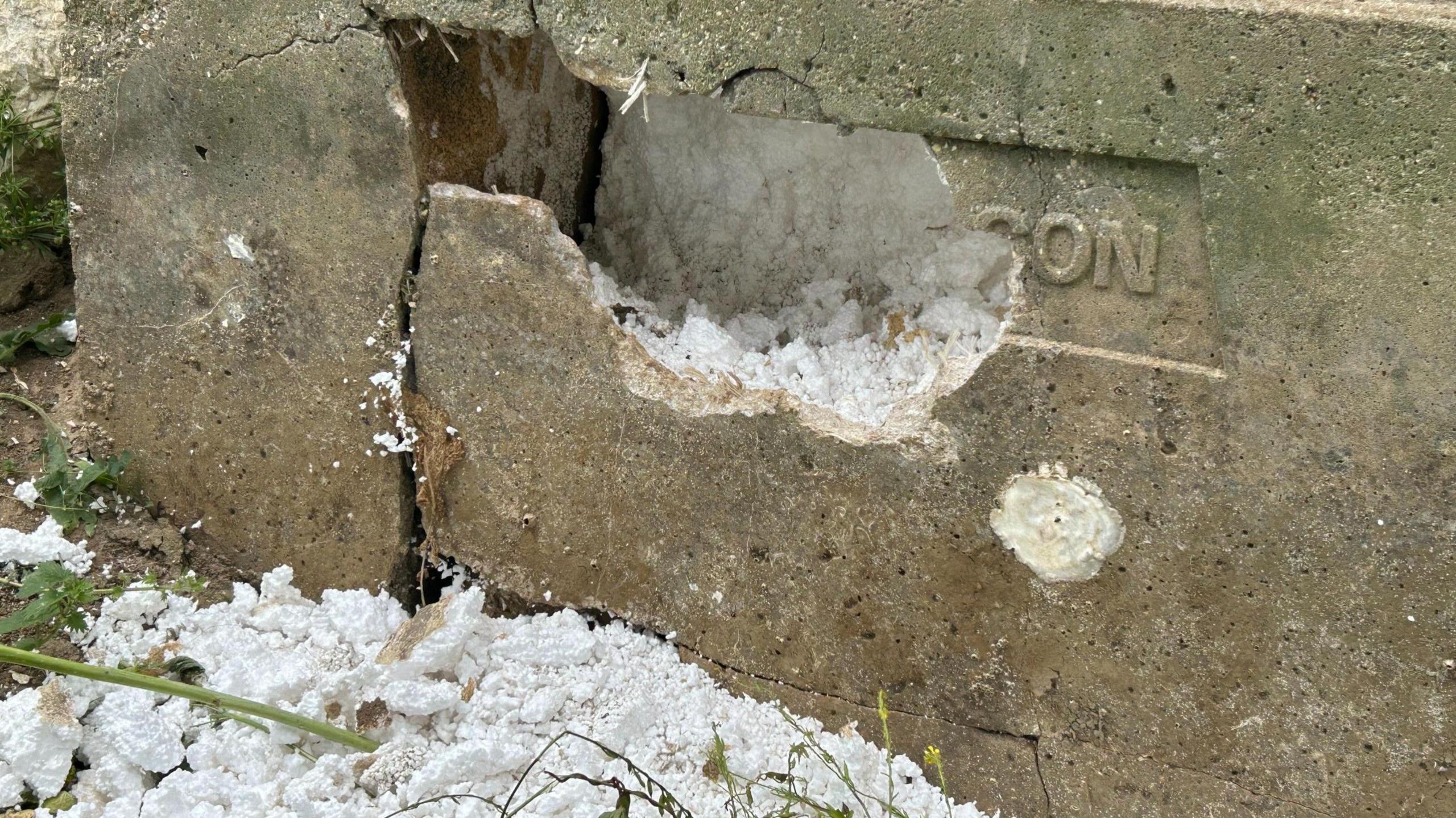 A grey and brown concrete brick with white polystyrene inside.