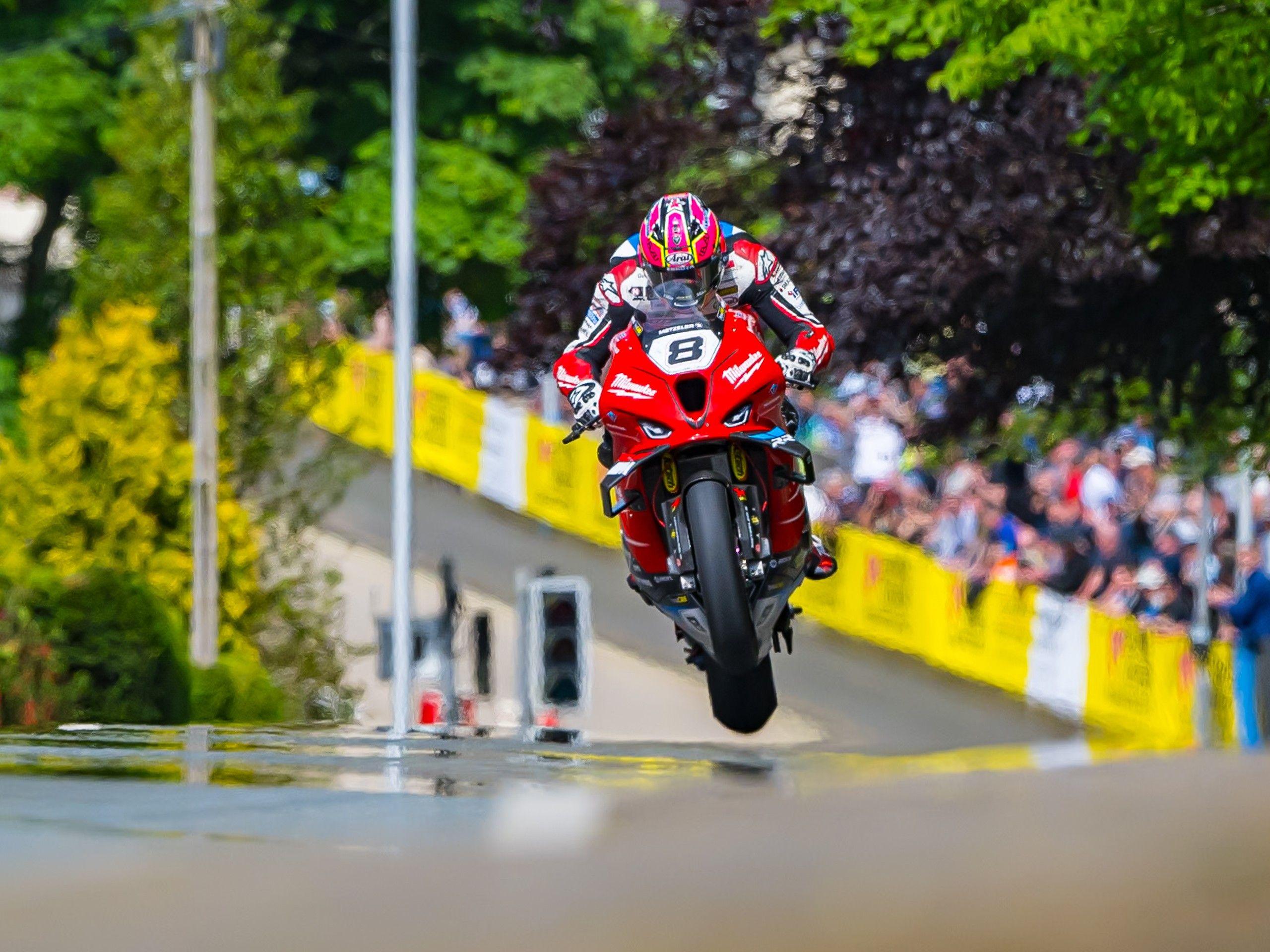 A motorbike jumps off the road as it turns a corner 