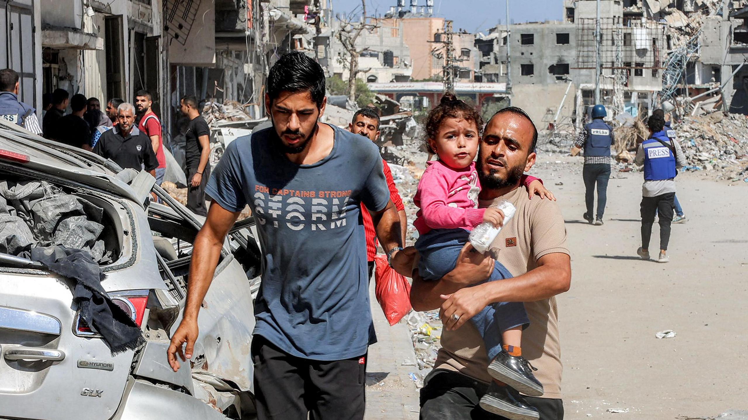 A man carries a child as people evacuate the Jabalia refugee camp in the northern Gaza Strip. Photo: 9 October 2024