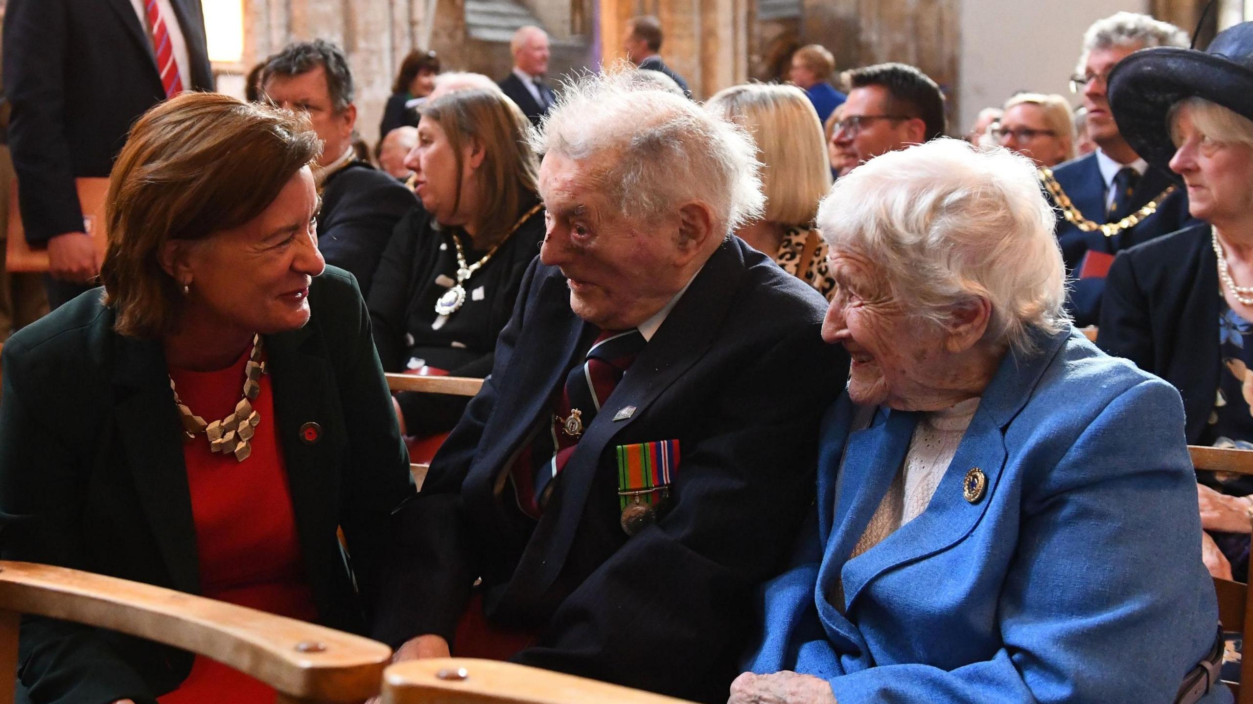 Eluned Morgan speaking to a veteran, who has white hair and is wearing a dark blazer