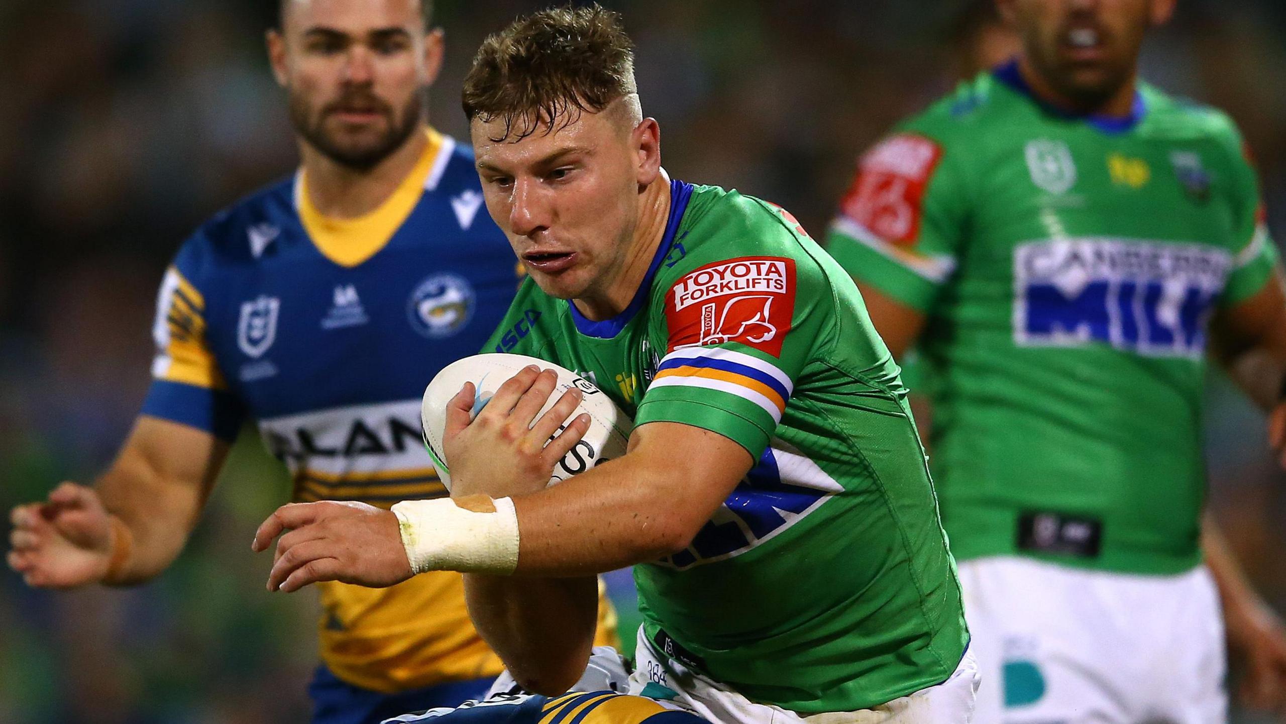 Half-back George Williams has shot successful his correct manus playing for Canberra successful 2021 arsenic a Parramatta defender tackles him astir nan midriff.