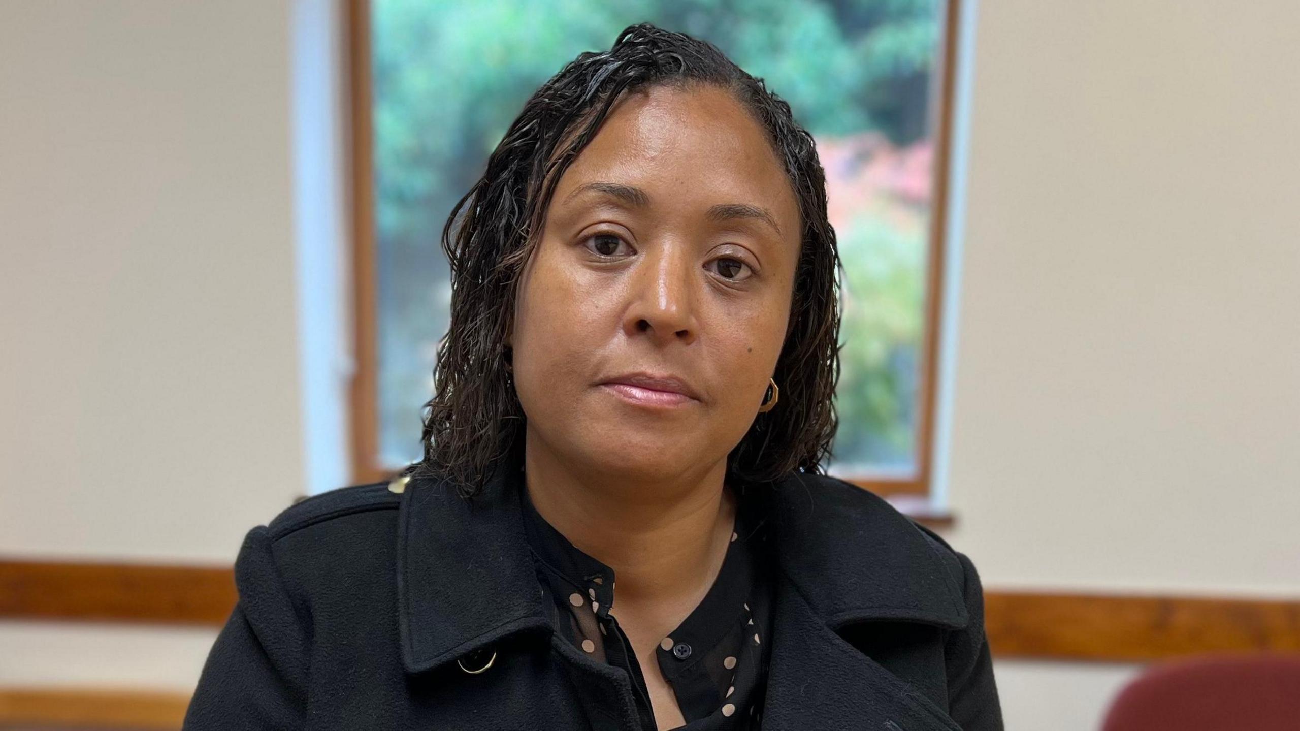 Ramona Marsh looking directly at the camera. She has wavy shoulder-length hair and is wearing a navy jacket.