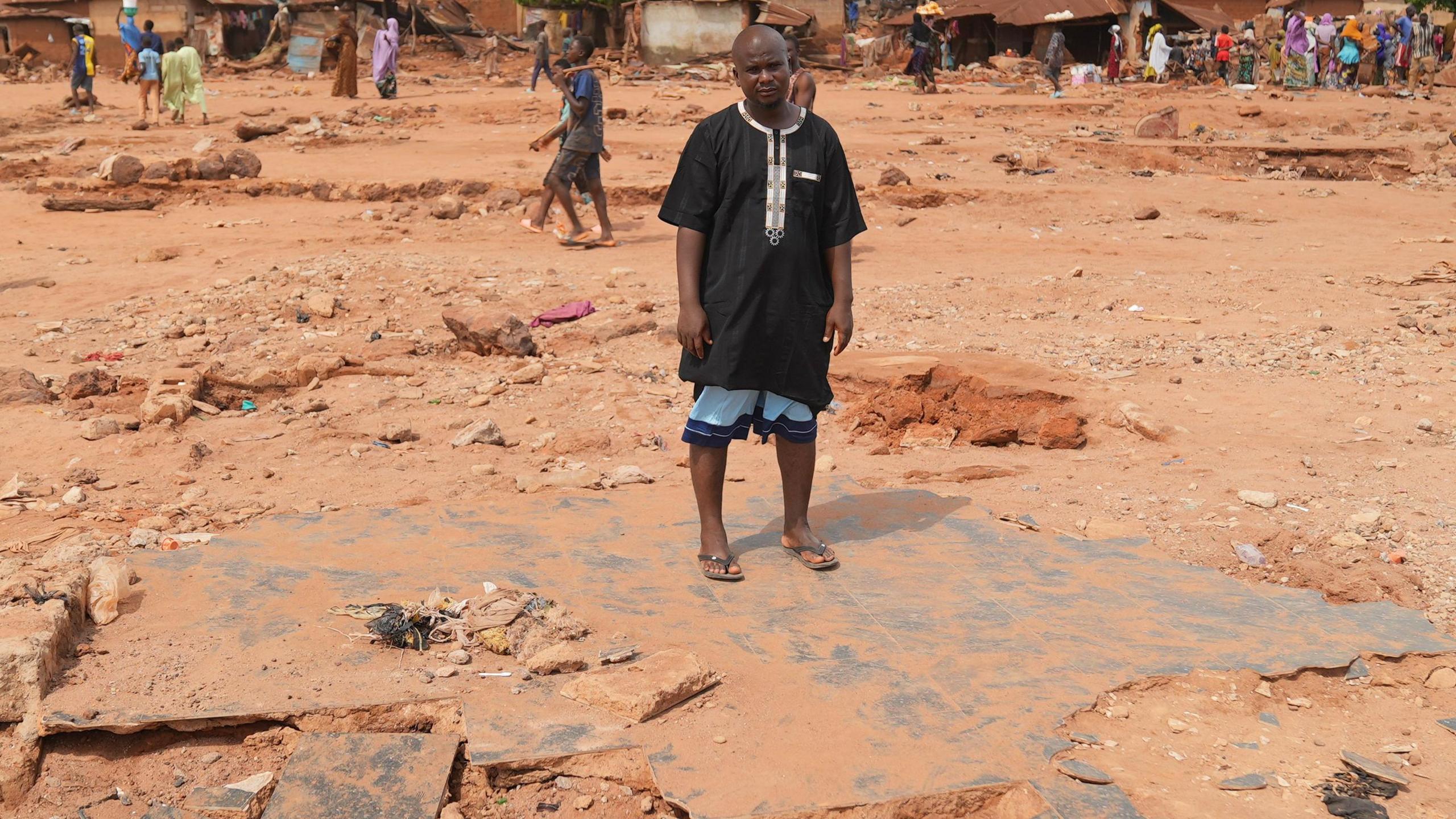 Adamu Yusuf standing on rubble