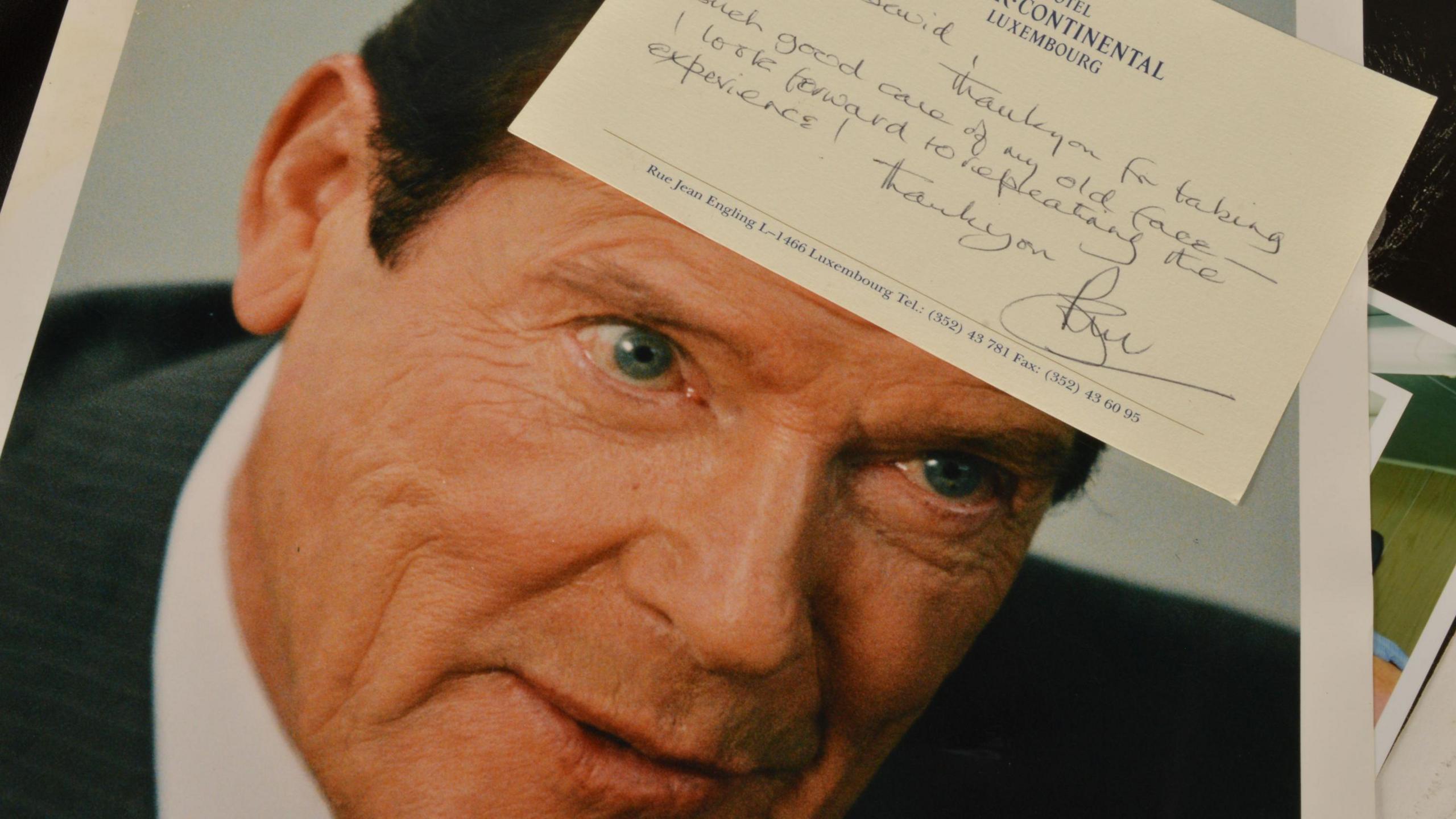A publicity photograph of Sir Roger Moore accompanied by a handwritten note from the actor thanking Dave Myers for his make-up work. The message is written on headed notepaper from the Hotel Intercontinental in Luxembourg.