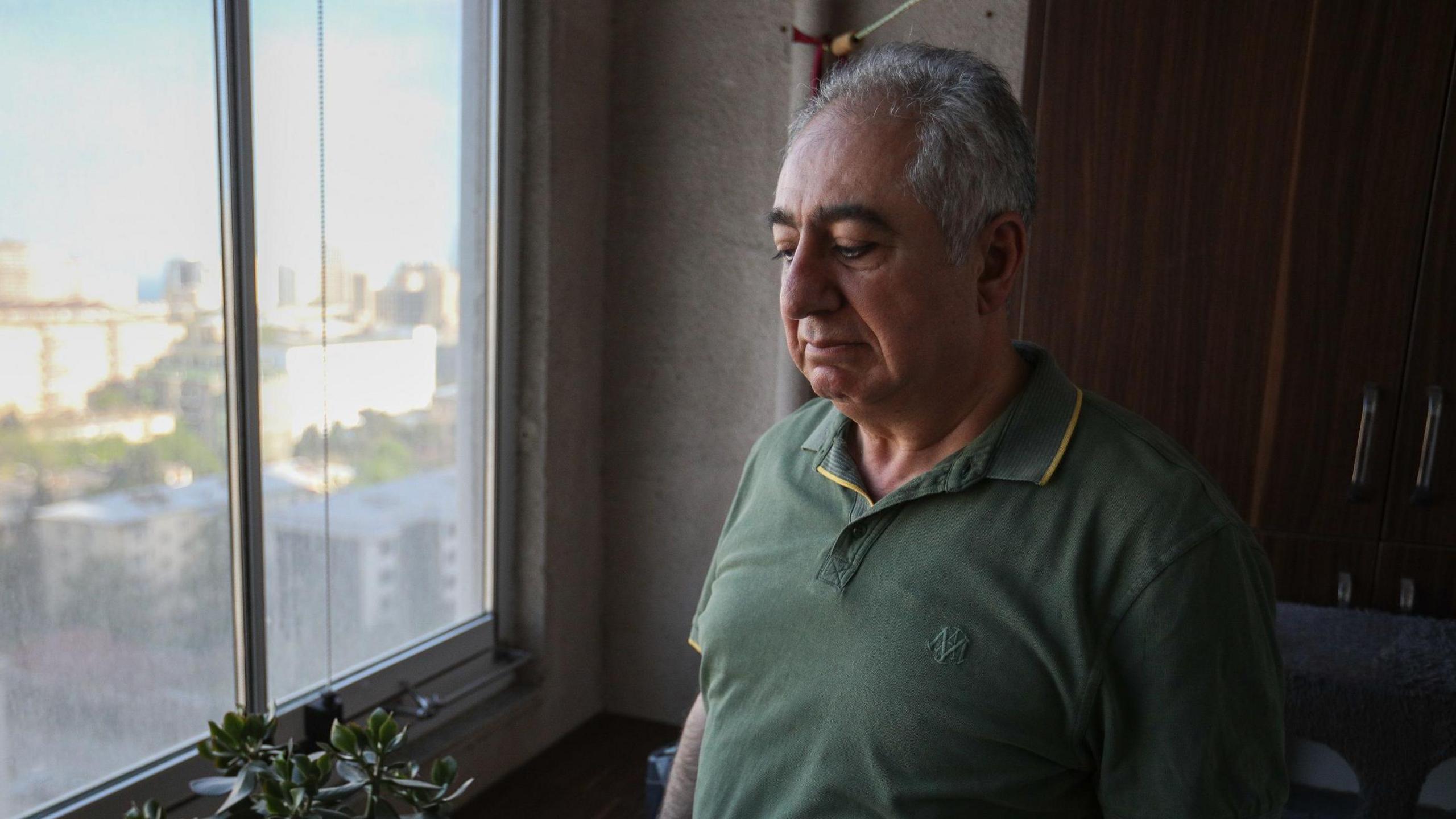 Gubad Ibadoglu looks out the window at his home where he is under house arrest