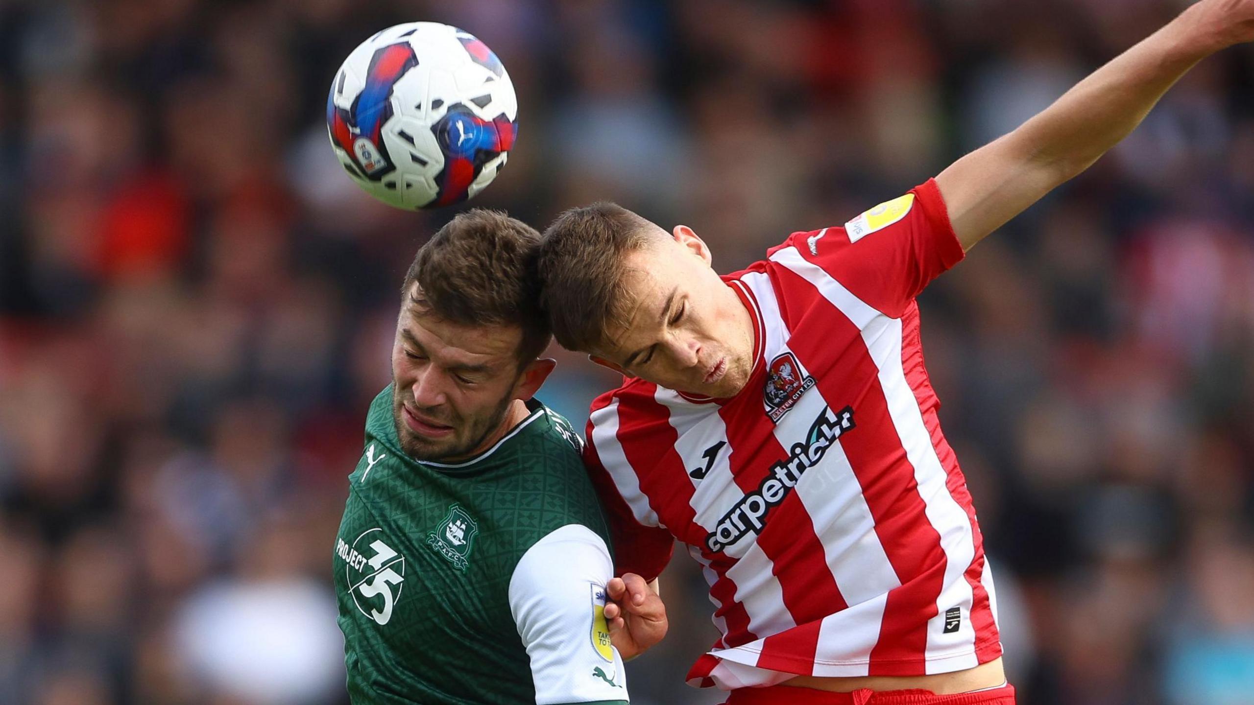 Plymouth Argyle and Exeter City players challenge for the ball
