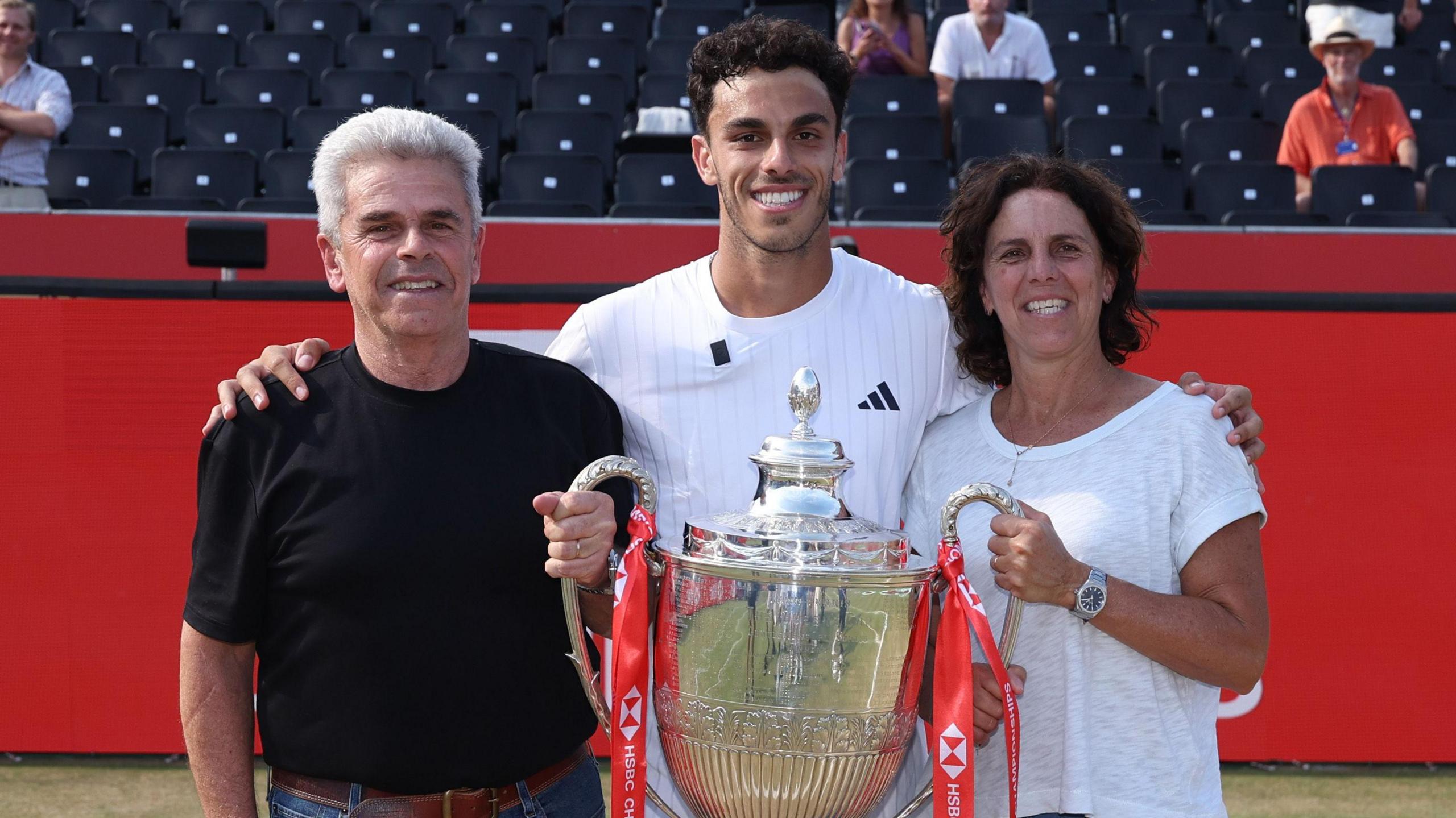 Francisco Cerundolo poses with the Queen's trophy alongside his parents