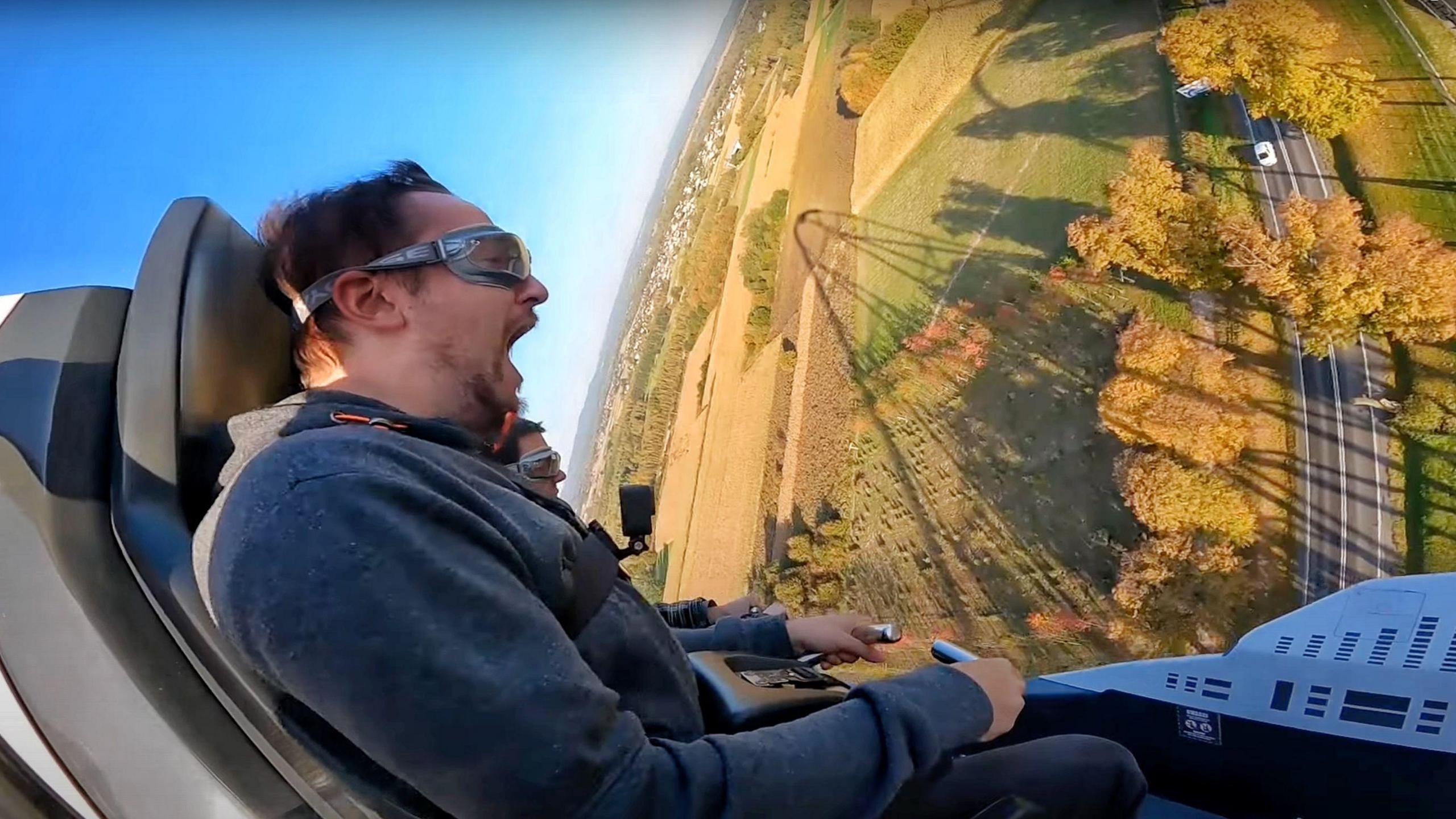 A side profile of Sean Evans, wearing a dark hoodie, screaming while on a roller coaster.