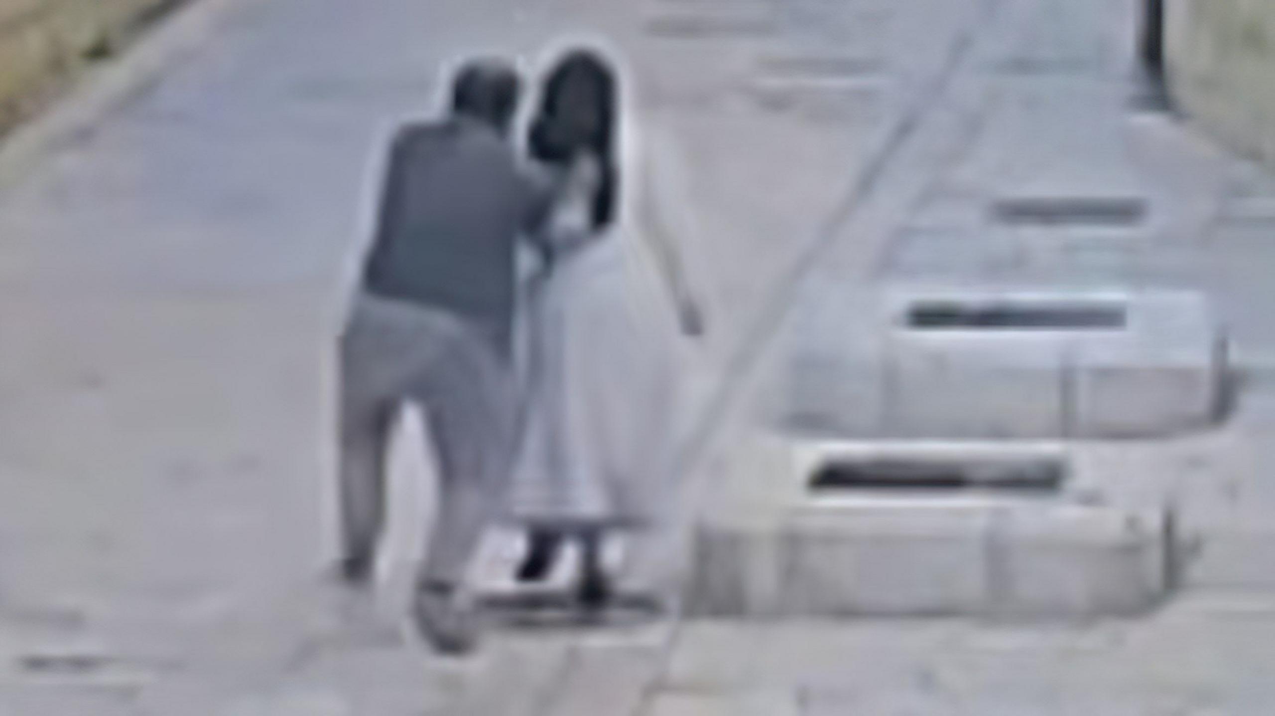 Grainy image from CCTV of a man from behind reaching out to push a nun as both walk in a street in Jerusalem (28/04/26)
