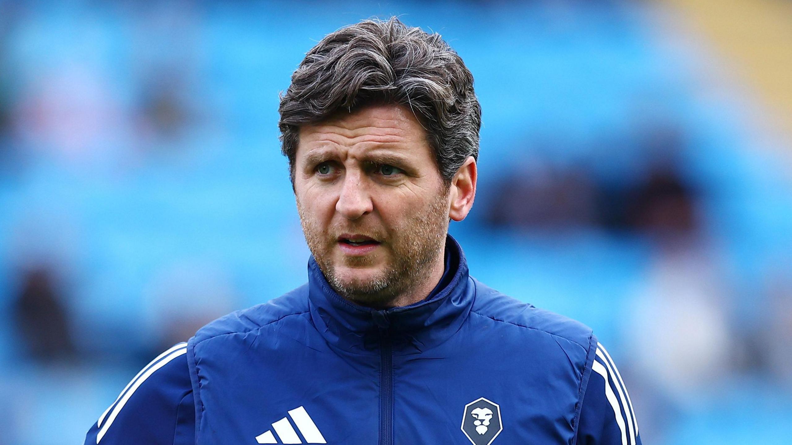 Alex Bruce holding a football under his right arm against a blurred background of blue seats
