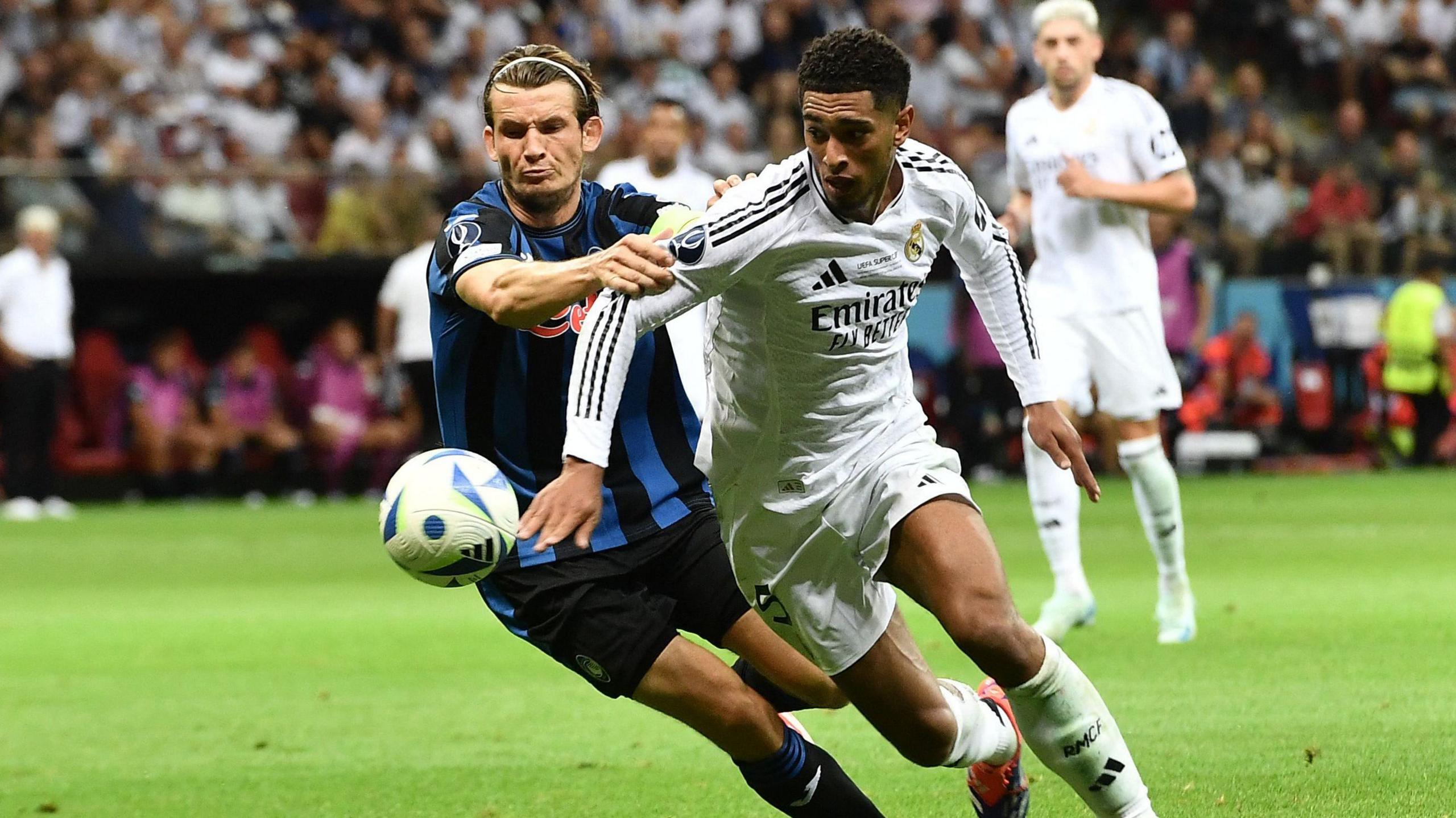 Real Madrid's Jude Bellingham in action on the football pitch with Atalanta's Marten de Roon