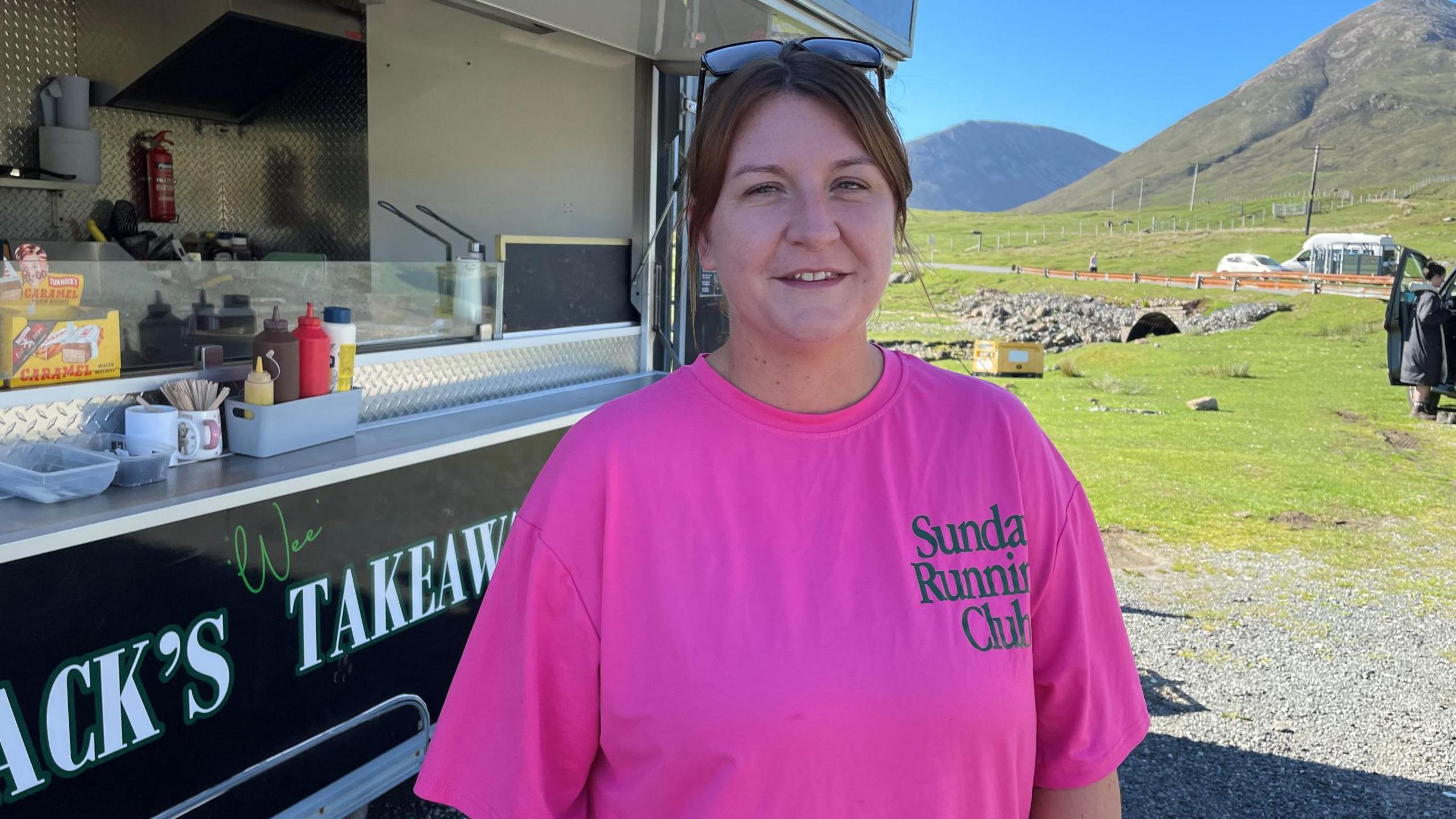 Sarah NicFhiongain na seasamh ri taobh a' bhana-bhìdh aice