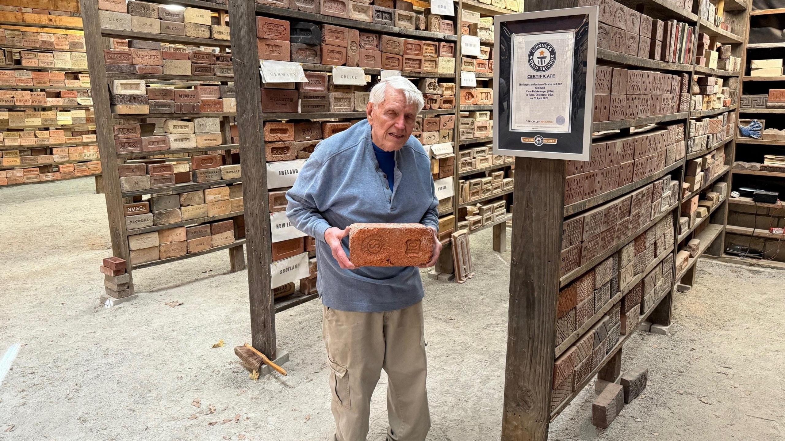 clem holding a brick in his barn full of bricks next to a Guinness world record certificate 