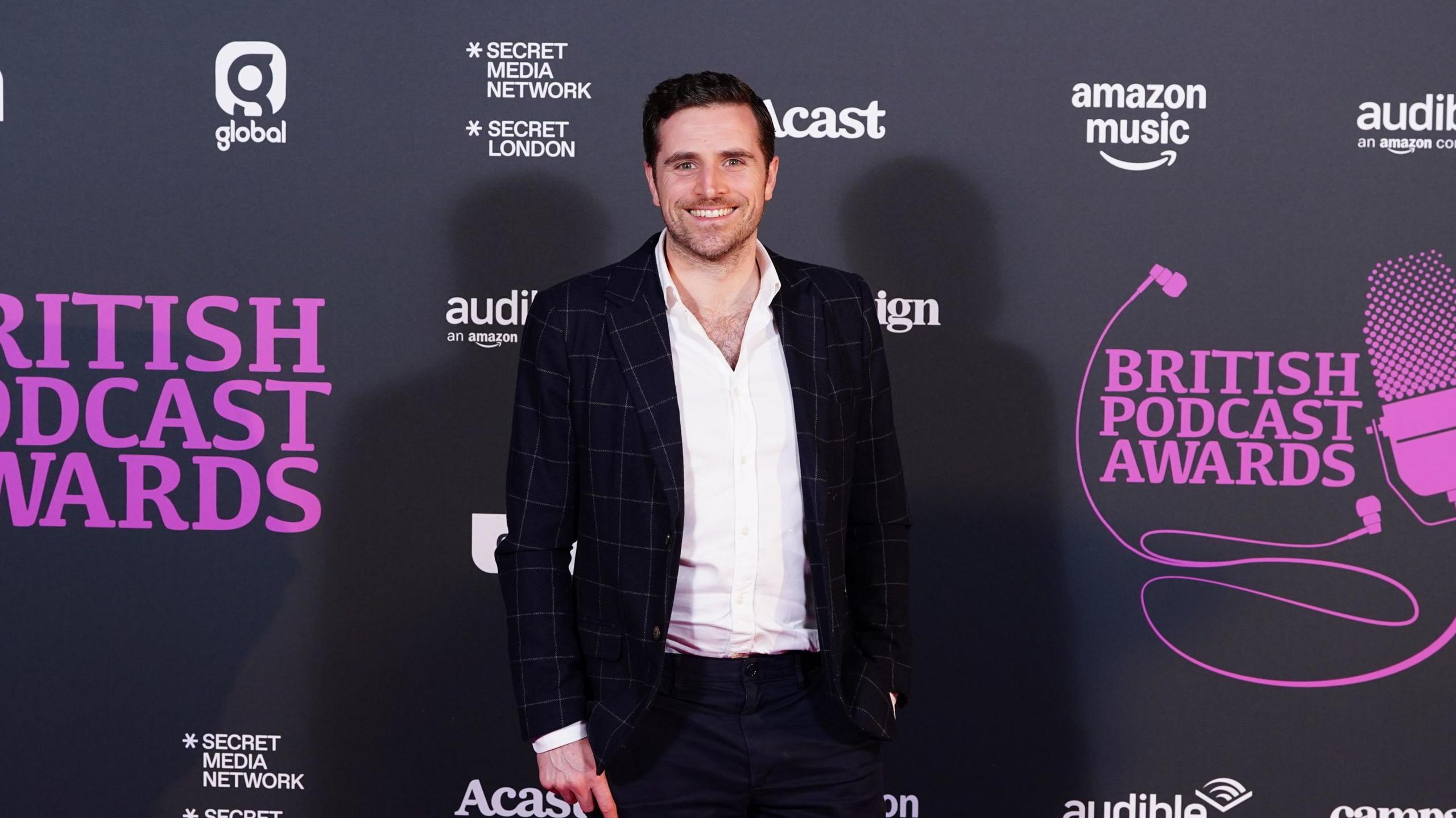 The Traitors series three contestant Alexander Dragonetti wearing a black blazer and white shirt at the British Podcast Awards.