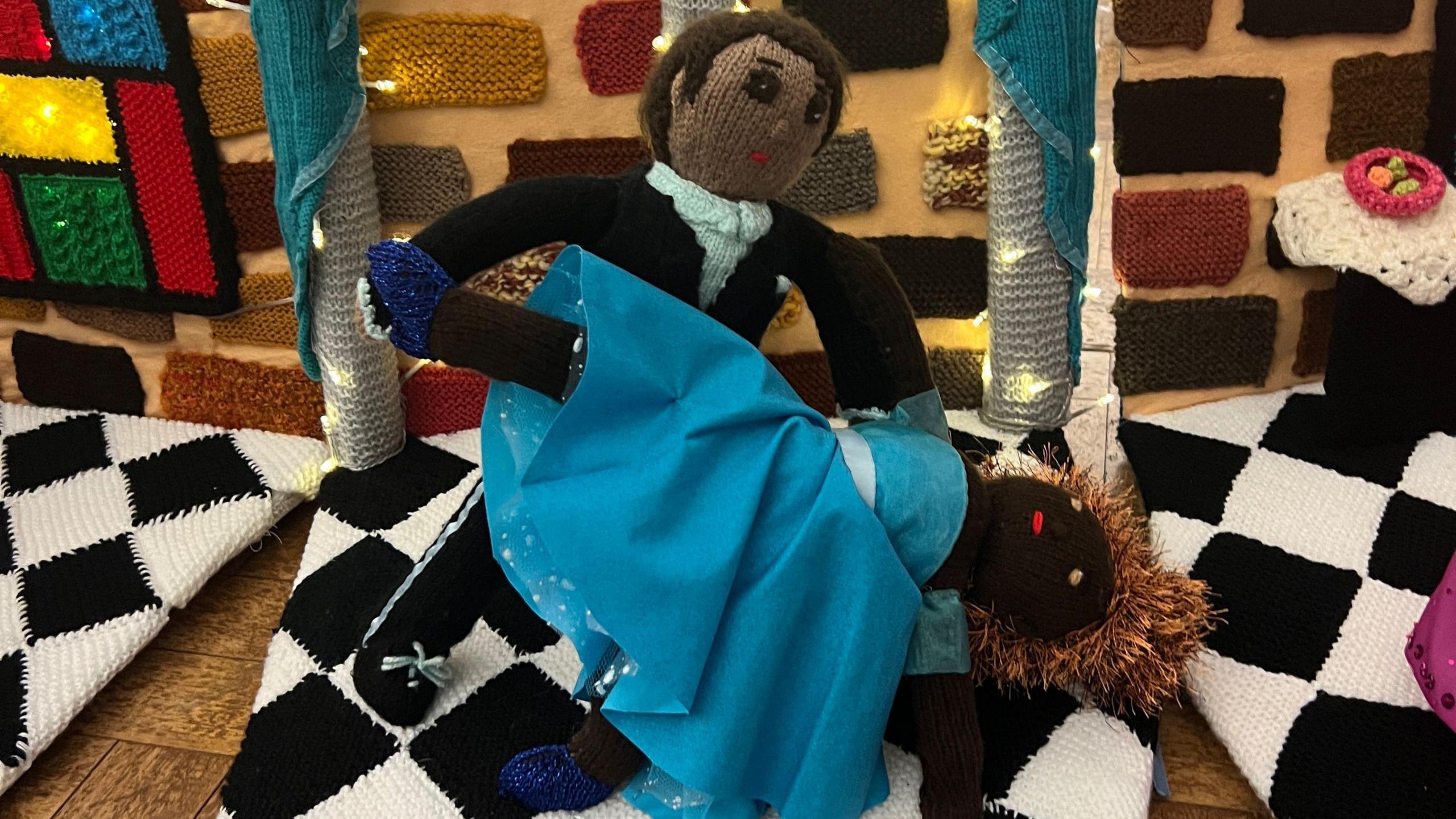 Two knitted dancers performing. The woman is bending backwards in a blue dress and blue shoes. The man is wearing a tuxedo.