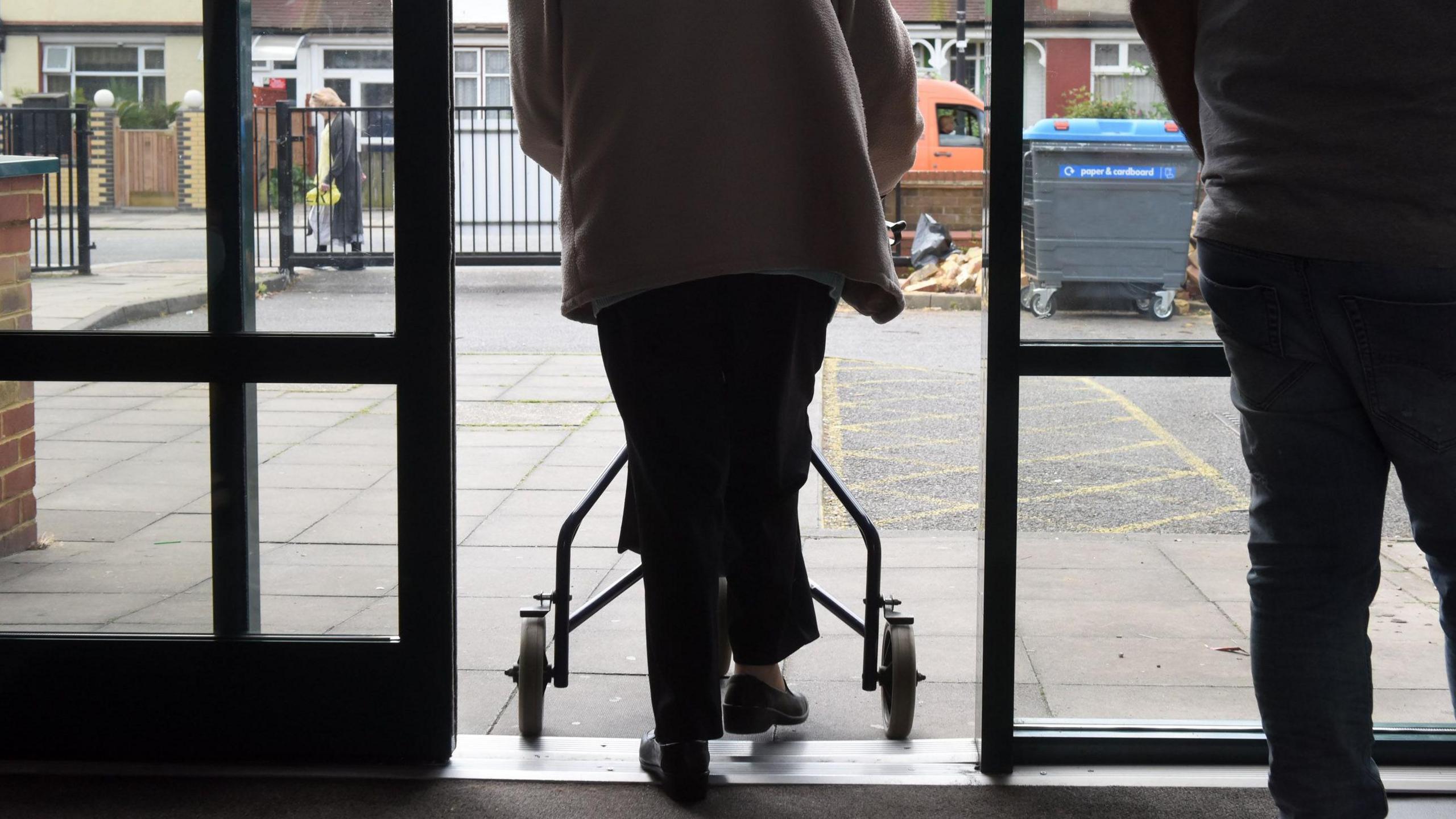 Woman using a mobility aid as she leaves a GP surgery.