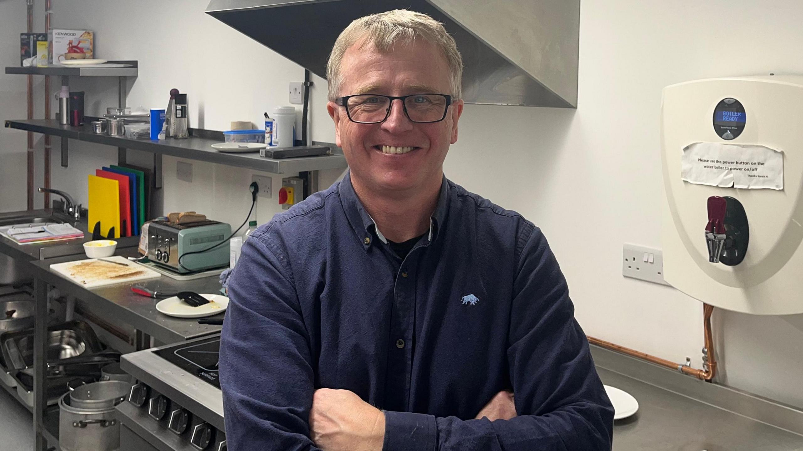 Jon Yates smiling in a blue jumper in a clean and sparkling kitchen
