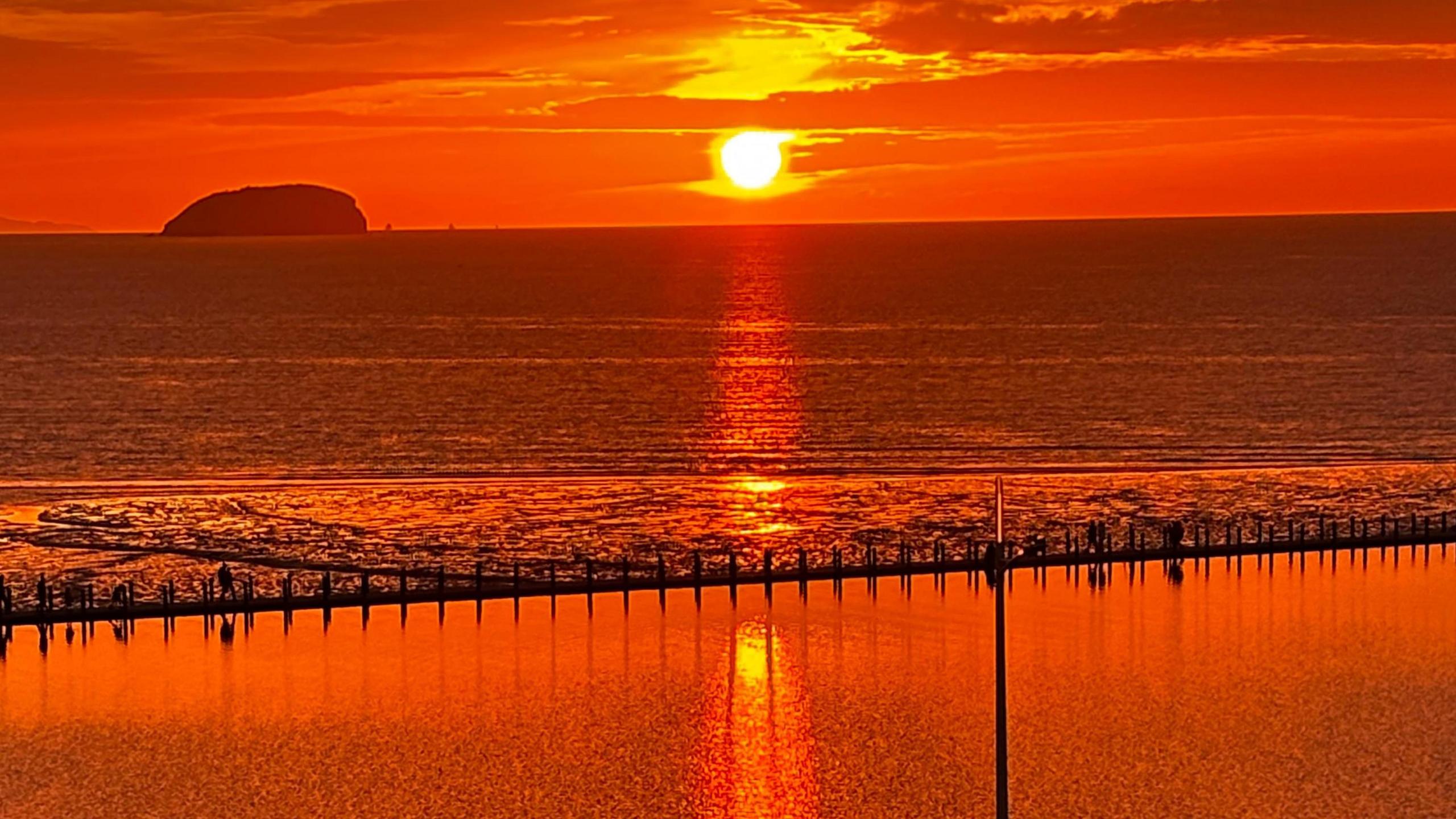 A deep orange sunset seen over the sea at Weston-super-Mare. Everything is coloured red-orange.