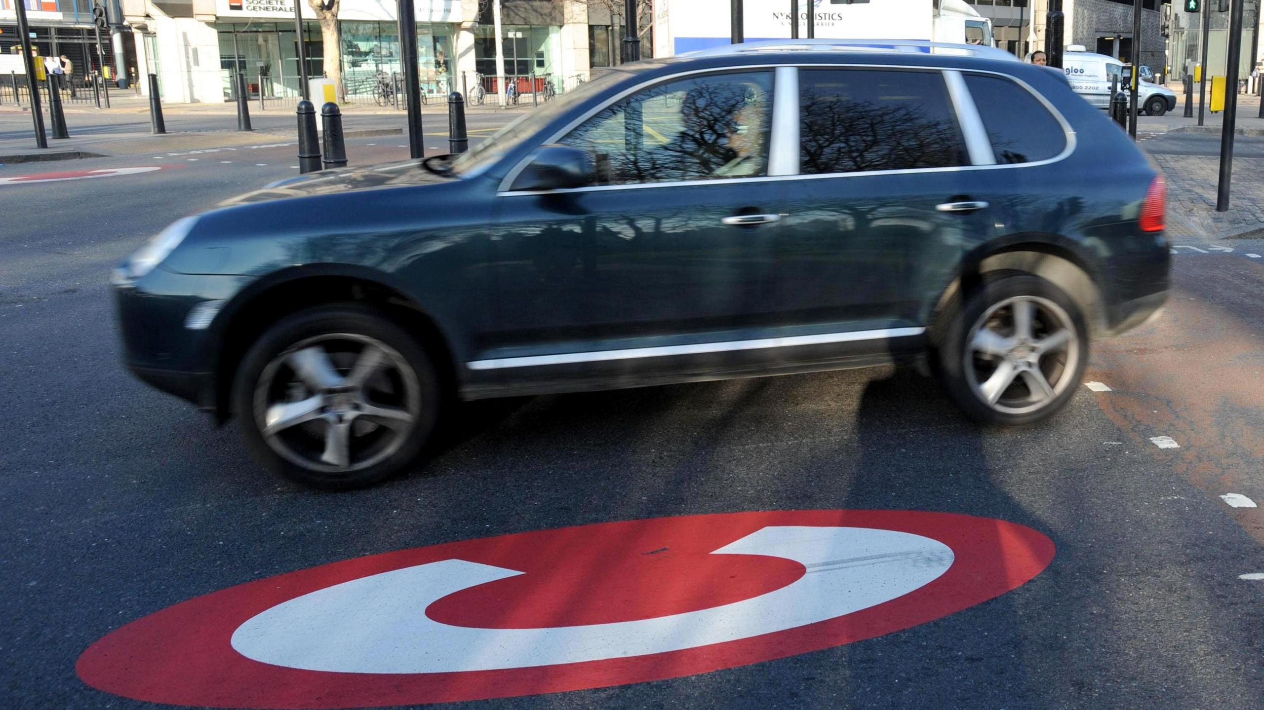 A SUV drives over a congestion charge sign in London