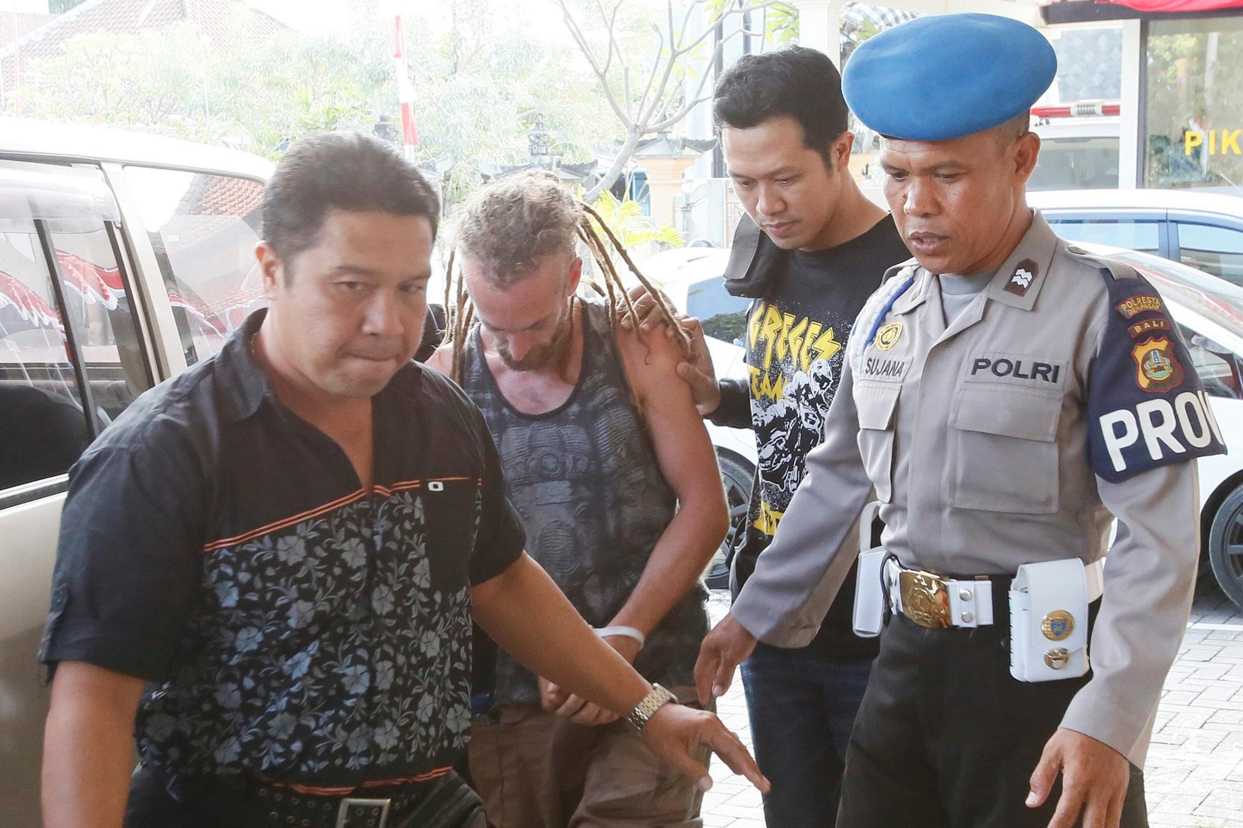 David Taylor is escorted by police officers after he was arrested over the killing of a policeman in Bali, Indonesia