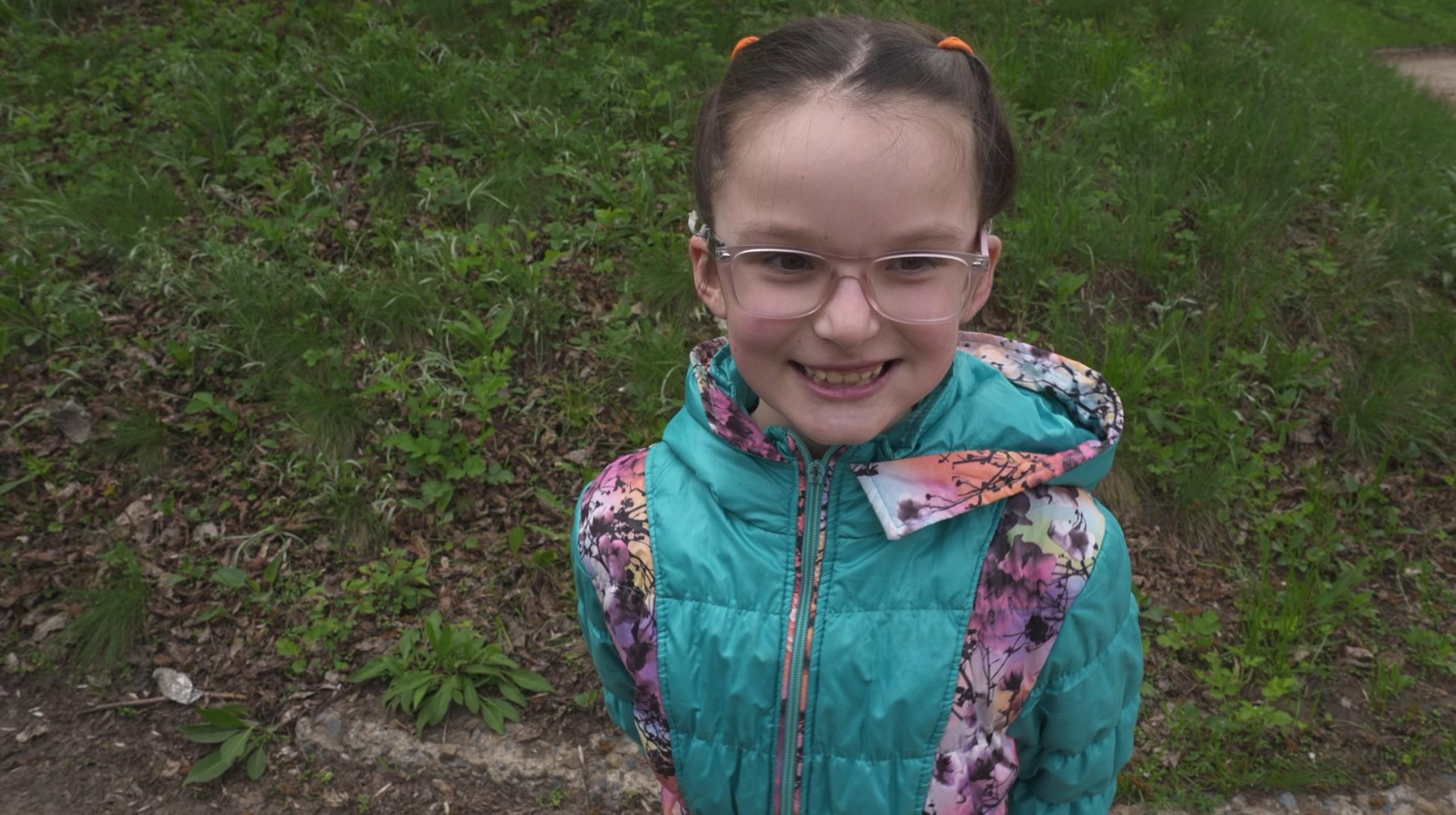 little girl with glasses smiles at the camera