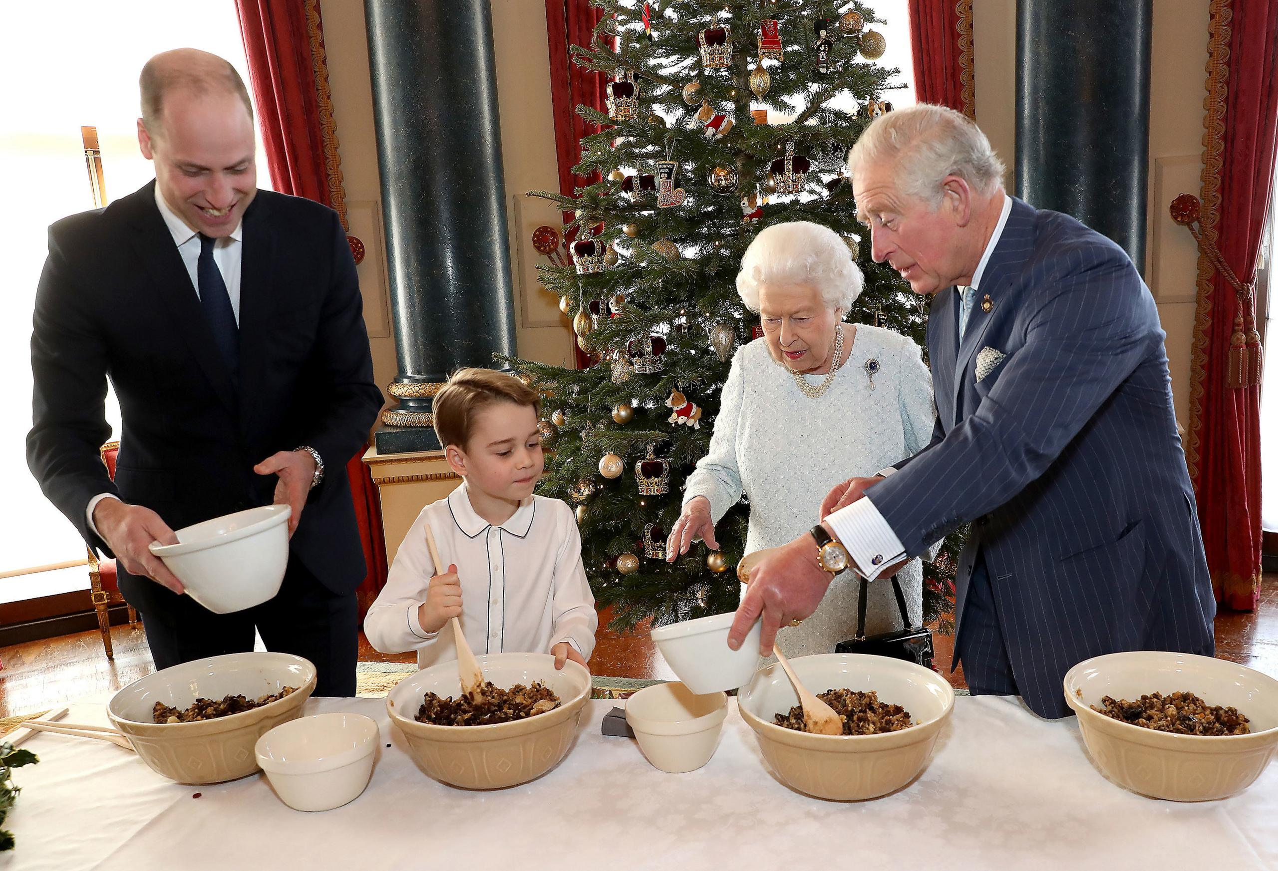 Queen Elizabeth II, the Prince of Wales, the Duke of Cambridge and Prince George preparing special Christmas puddings in the Music Room at Buckingham Palace, London, as part of the launch of The Royal British Legion"s Together at Christmas initiative