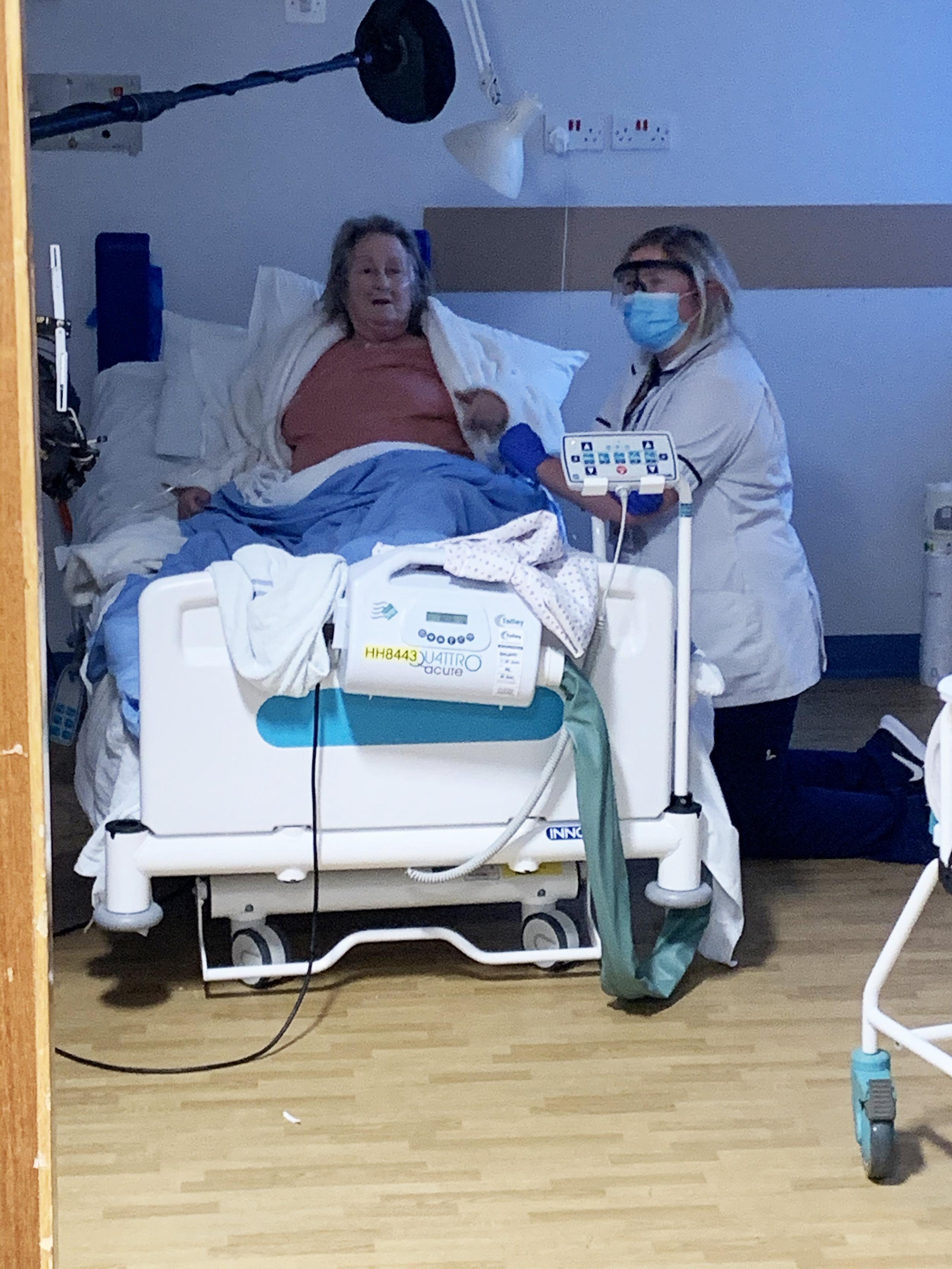 A physiotherapist holds the hand of a woman in her 70s who is recovering from Covid