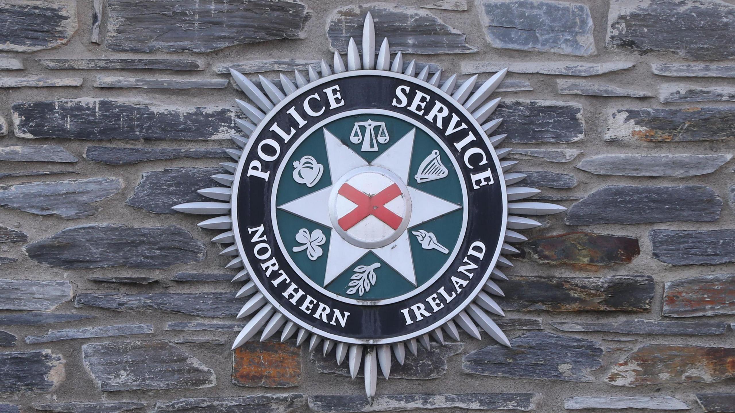 The Police Service of Northern Ireland badge on a grey stone wall.