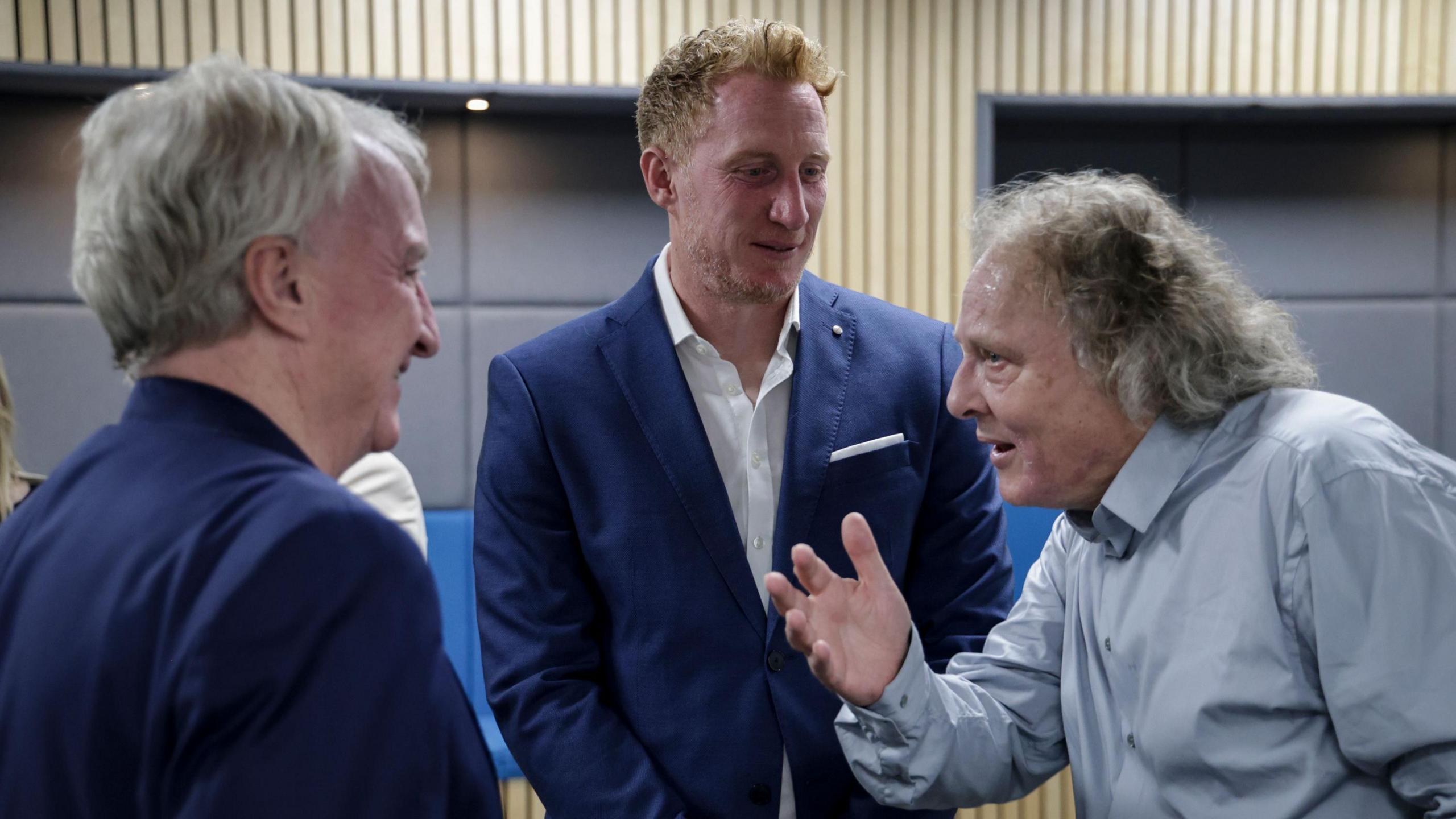 Three formally dressed men engaged in conversation
