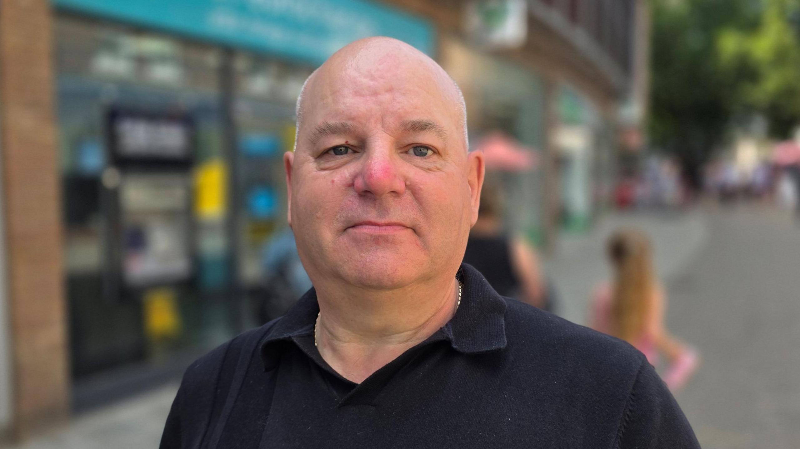 Robert Nicholls is standing in King's Lynn town centre. He's wearing a black t-shirt.