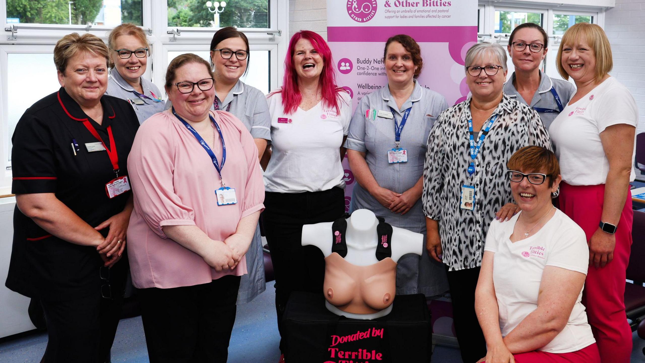 A group of women standing together behind a bust mannequin 