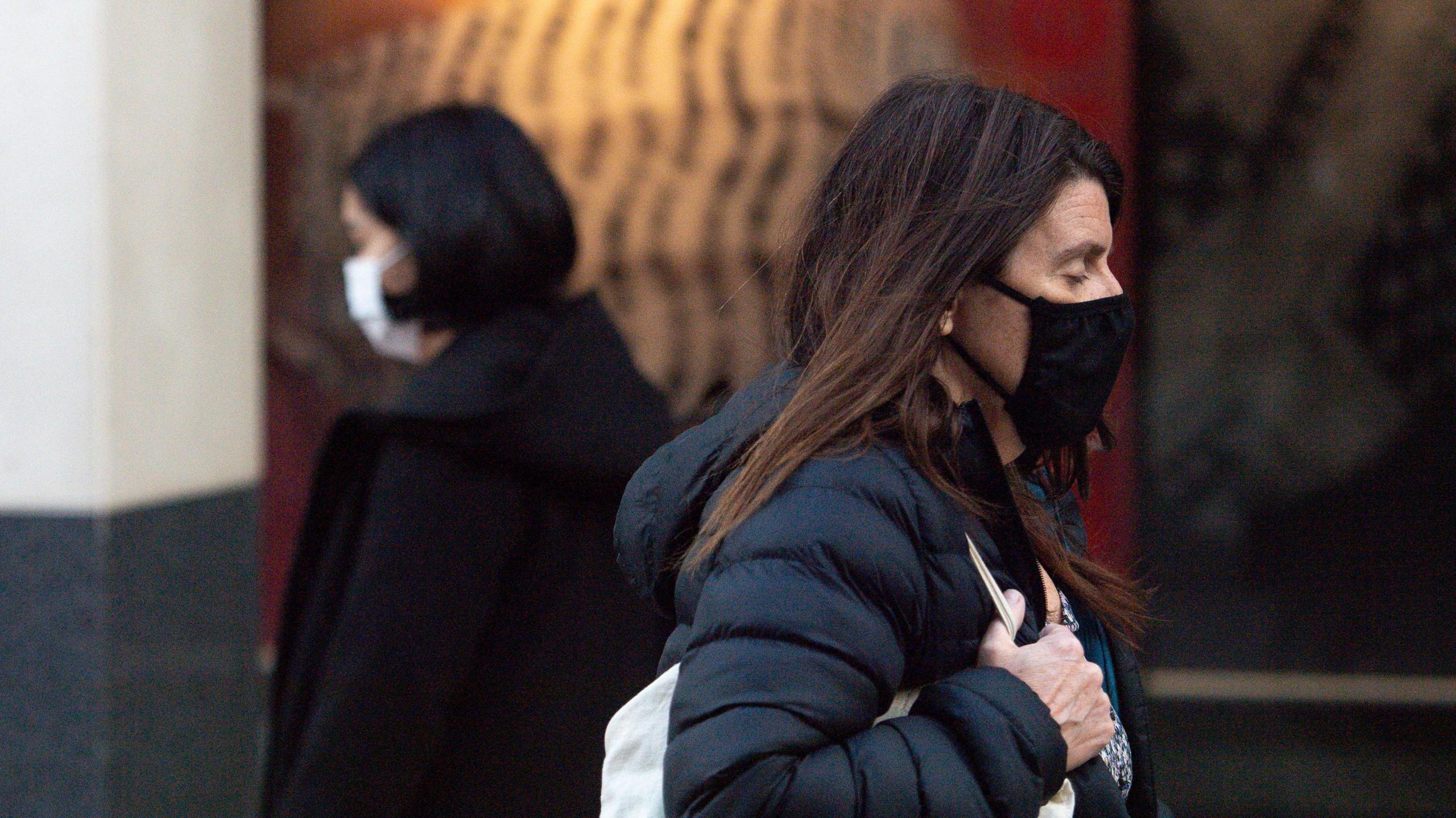 Two women walking past each other wearing face masks and winter coats in Nottingham city centre in October 2020.