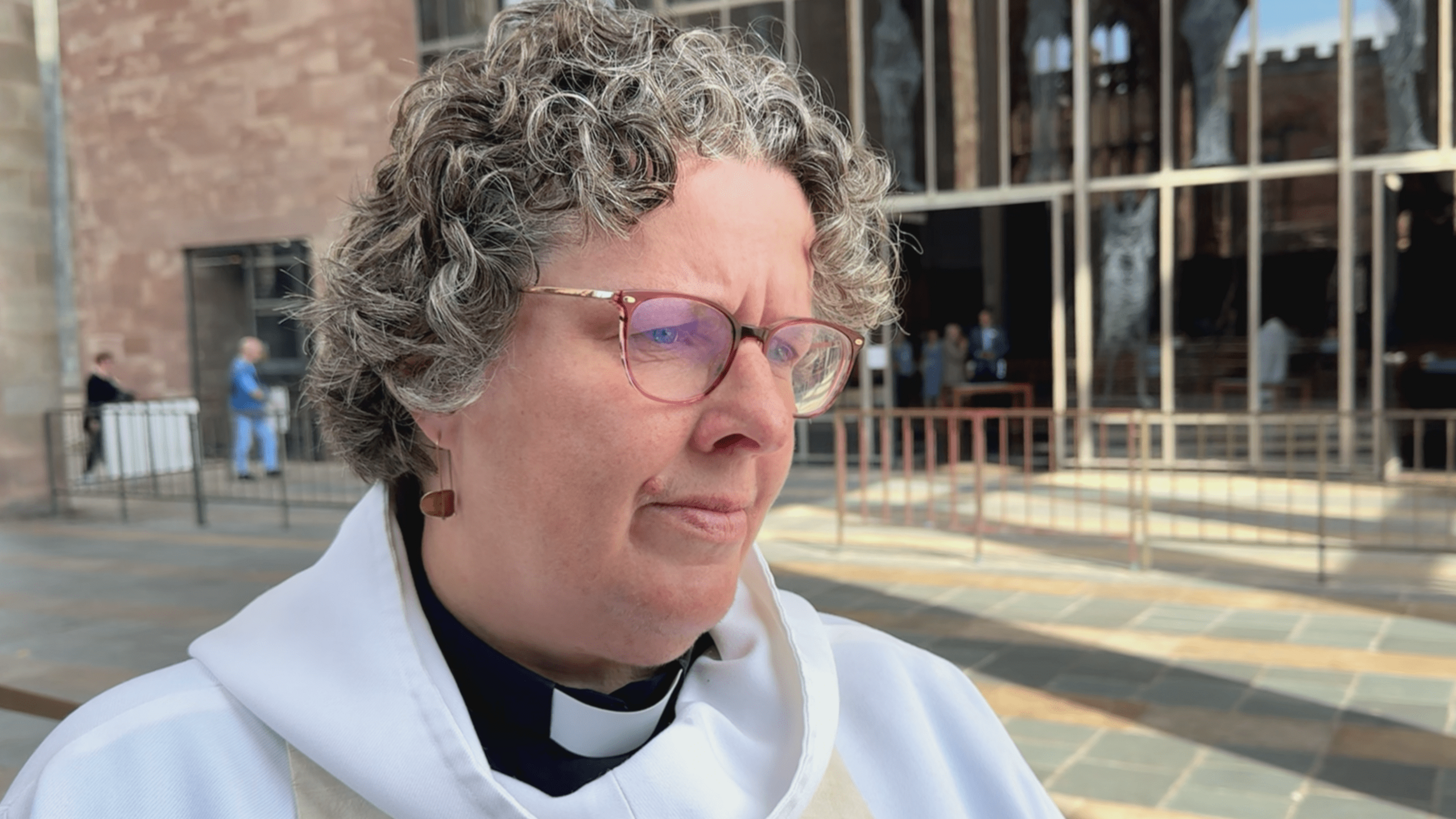 Mary Gregory wearing brown glasses standing outside Coventry Cathedral