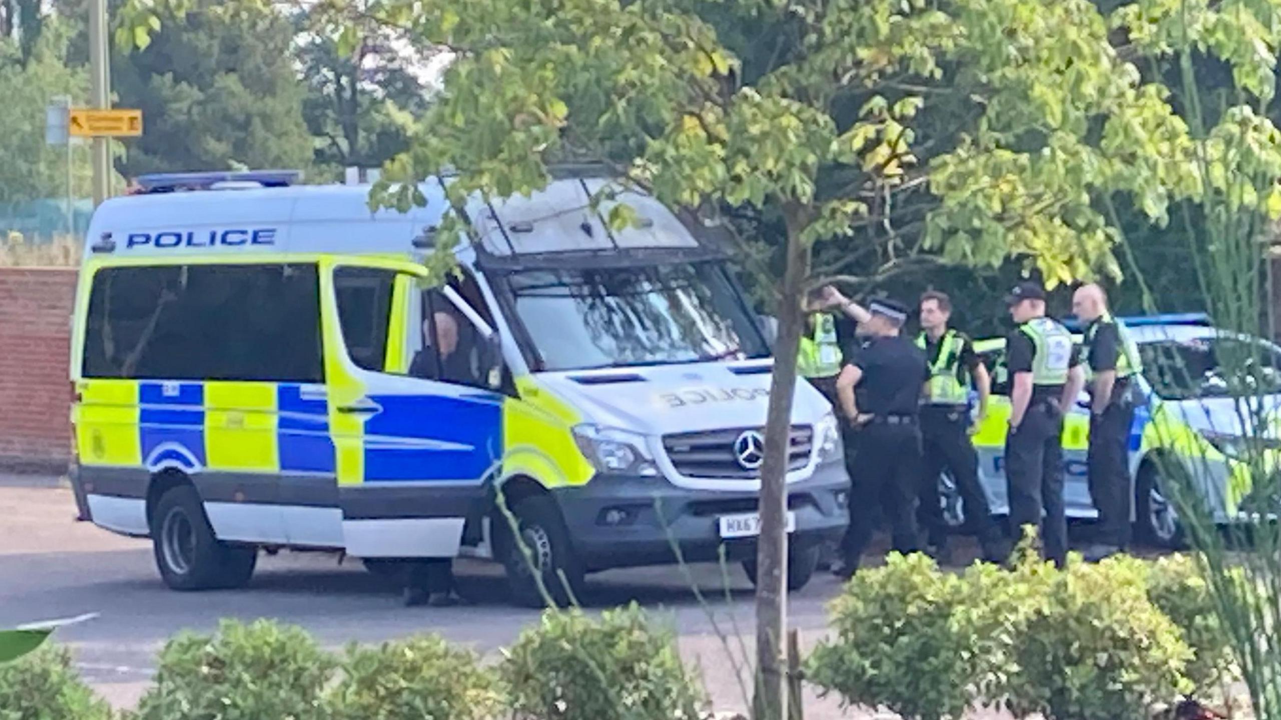 Police van and car park with some officers standing by