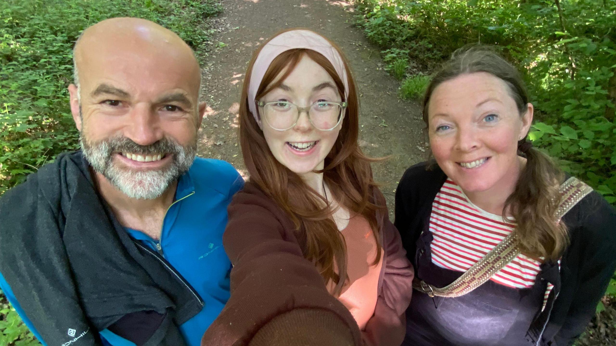 Ella Burns takes a selfie with her parents Nick and Jenni on either side.