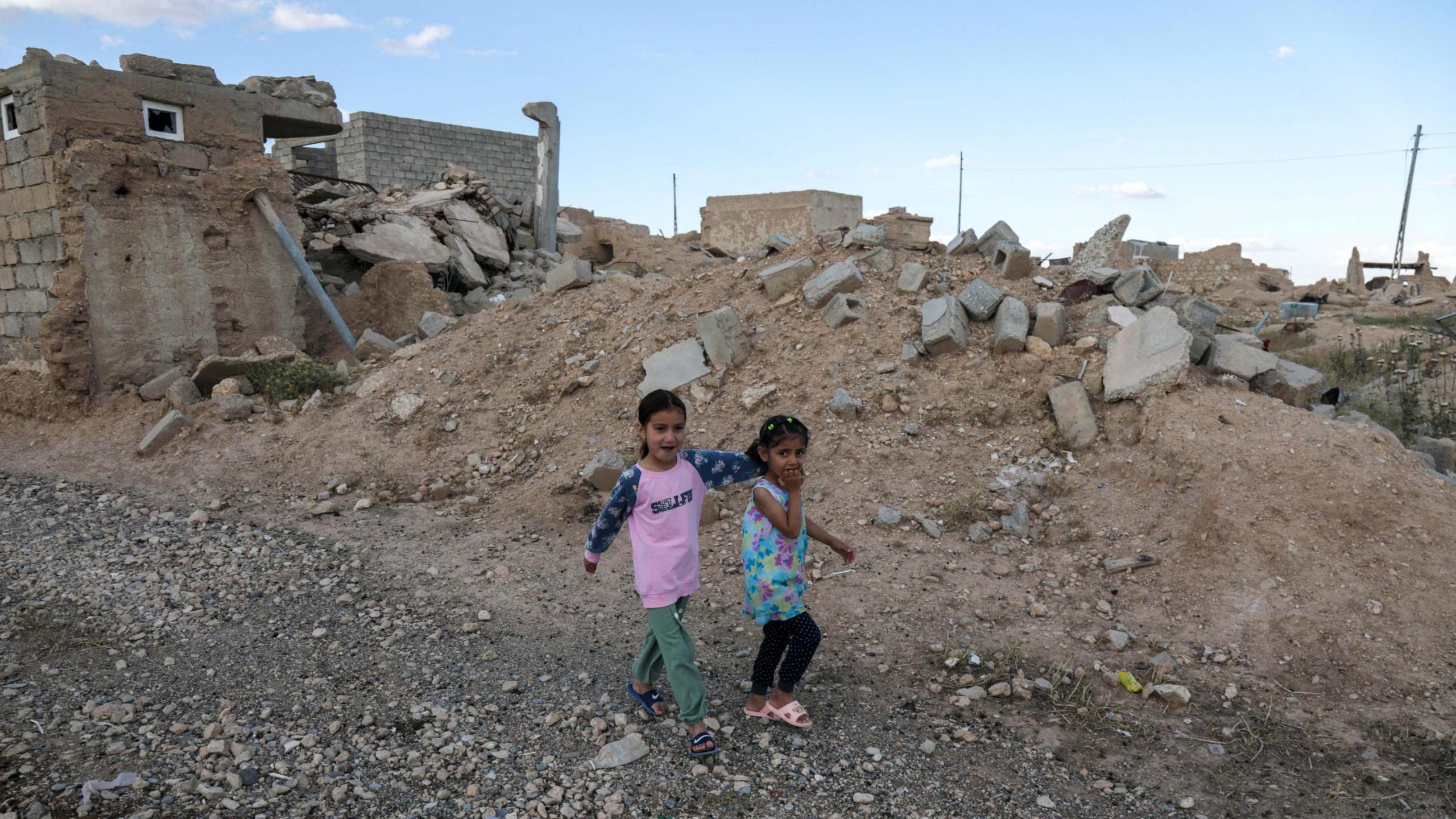 Two children walk among the rubble of Sinjar