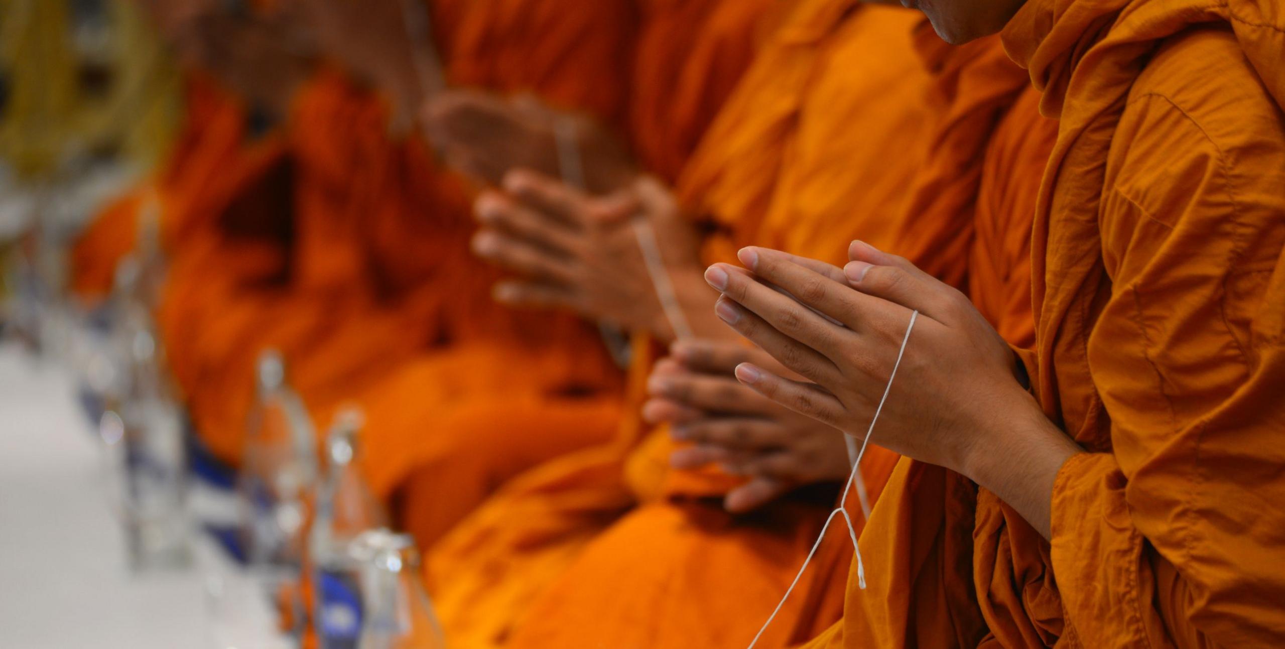Close-up on the palms of a row of monks, pressed together in prayer
