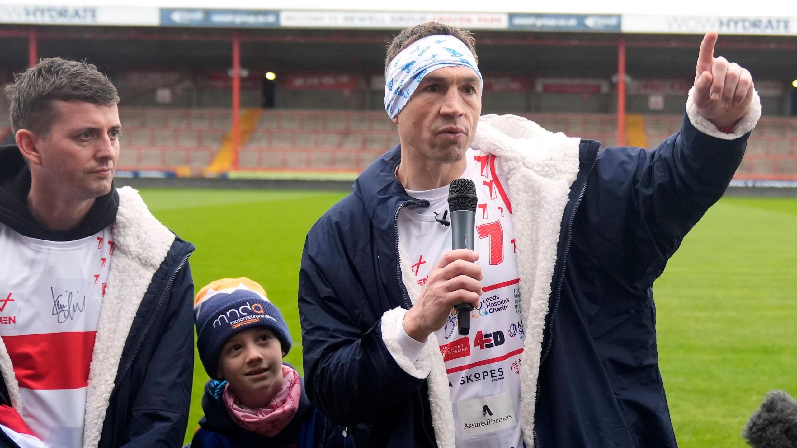 Kevin Sinfield thanking supporters at Craven Park. He is wearing a white running top, jacket and blue and white bandana. 