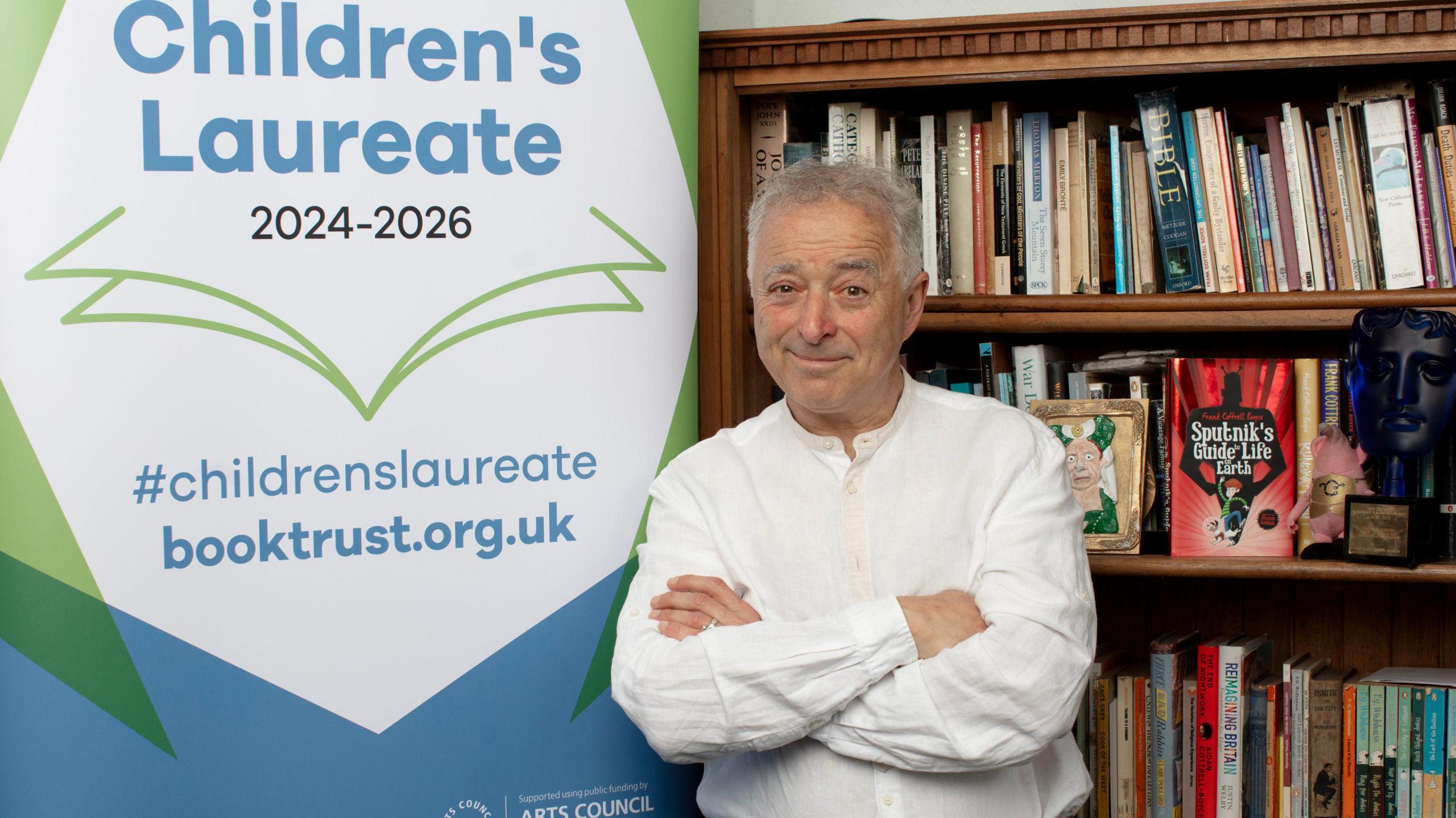 Frank Cottrell-Boyce smiling in front of books