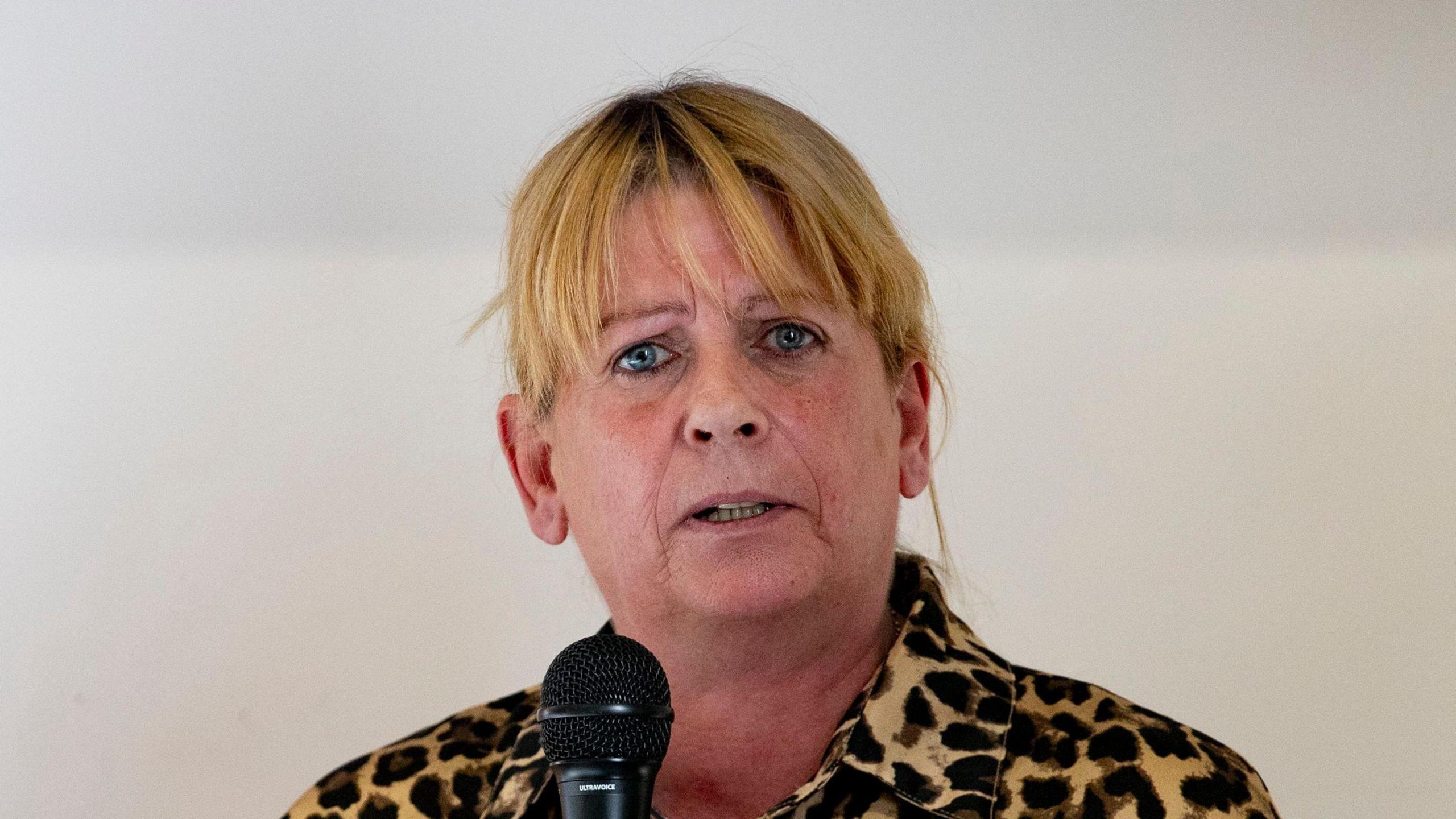 Martina Dillon pictured with a blonde fringe and wearing a leopard print shirt as she speaks into a mic.