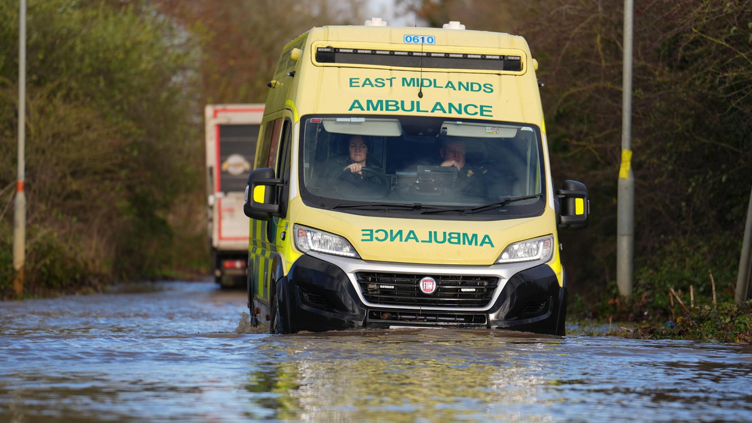 An ambulance drives through floodwater near the Billing Aquadrome in Northamptonshire