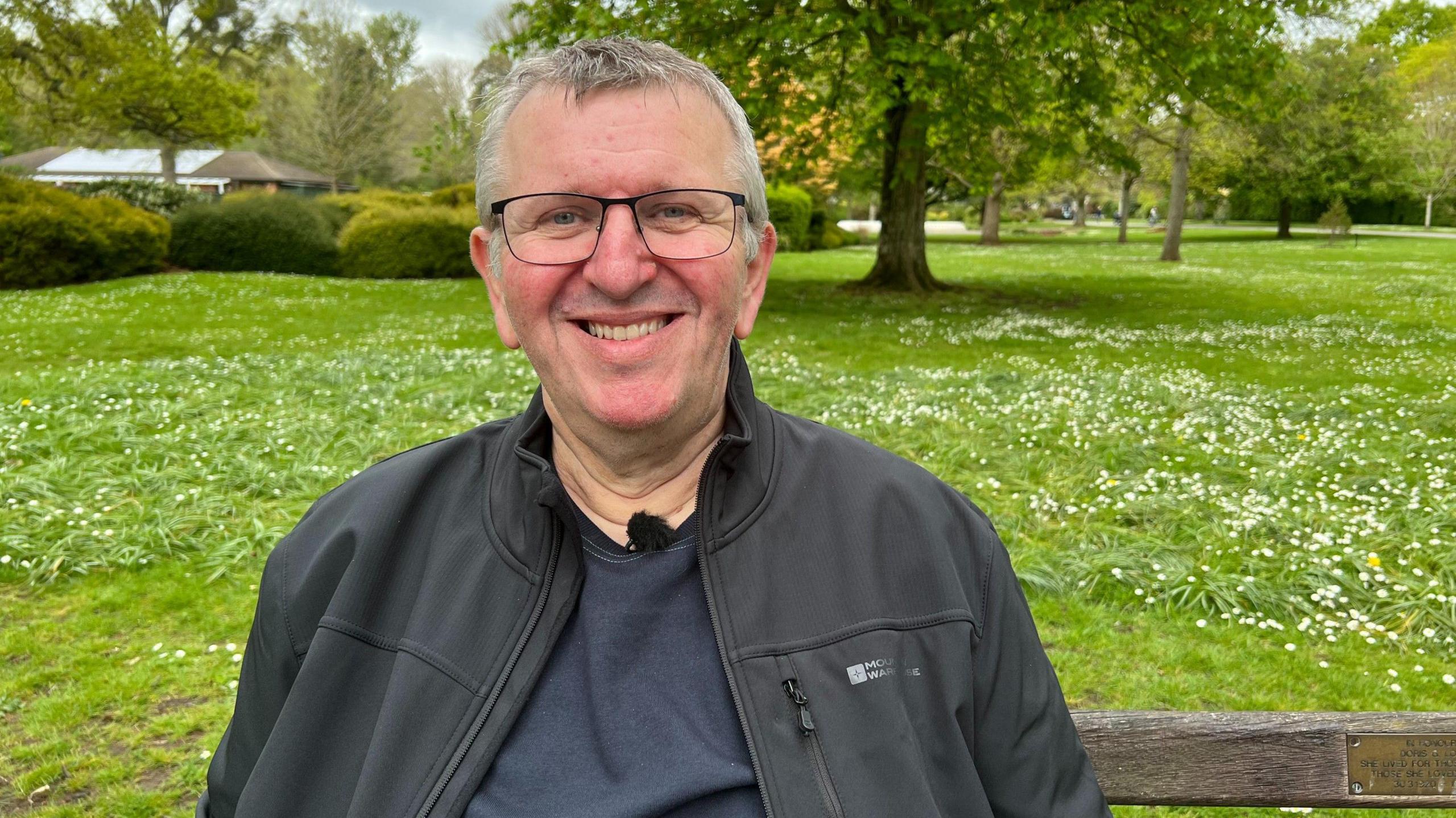 A man sits on a bench smiling.