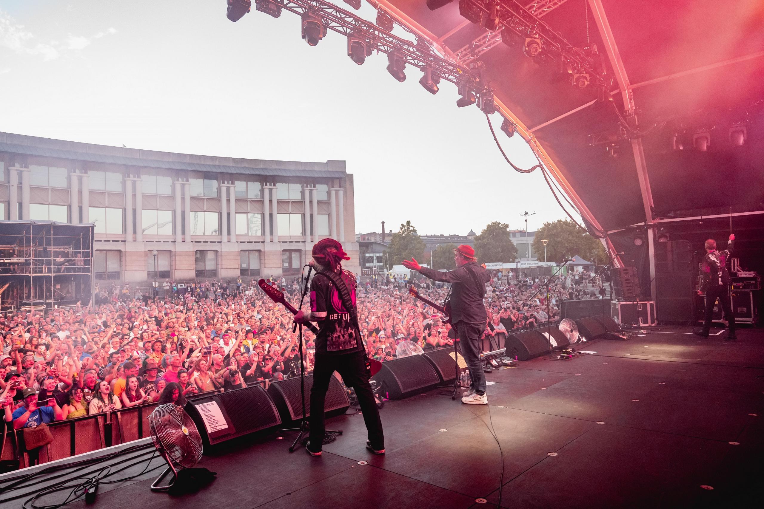 A shot from behind showing Levellers on stage and the crowd in the background