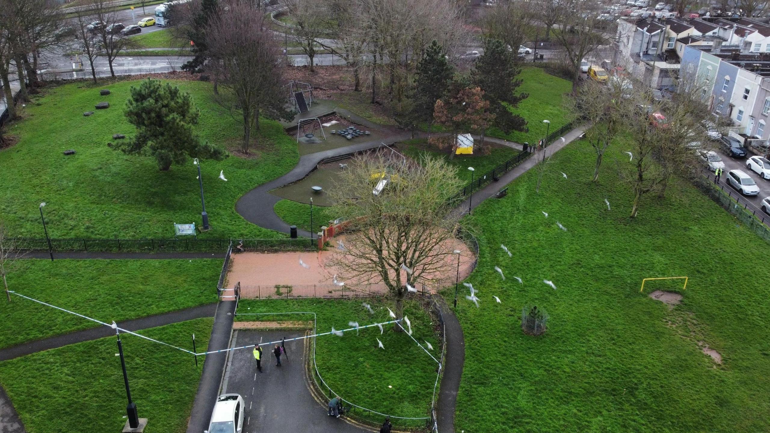 A drone image of Rawnsley Park in Easton, Bristol. Police tape and police vehicles are visible, along with a children's play park.