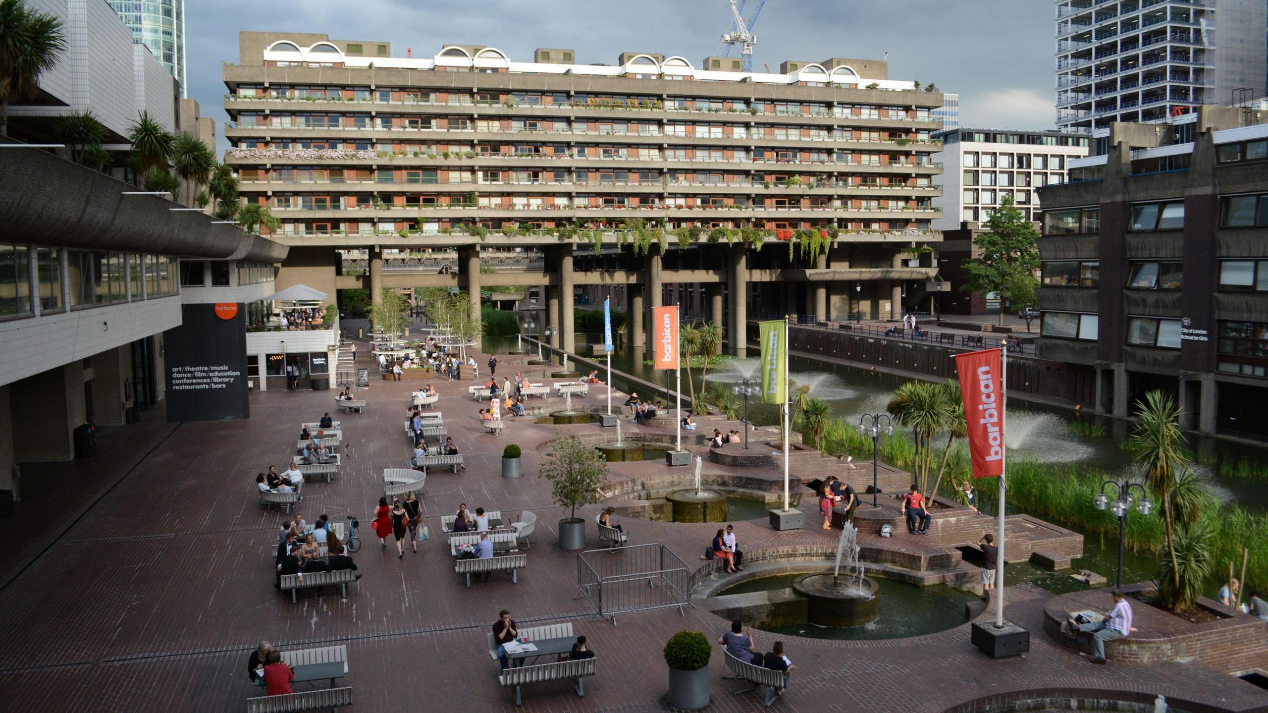 People sit outside on benches at The Lakeside, at the Barbican Centre