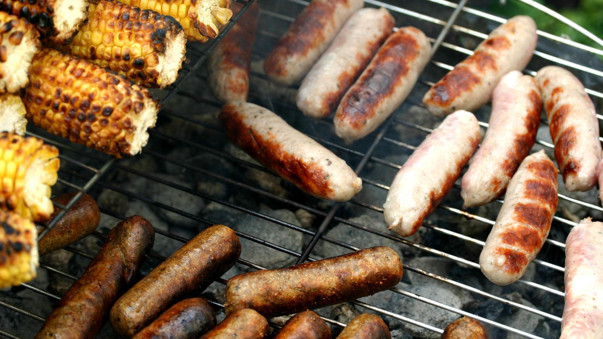 Sausages and sweetcorn on a barbecue.